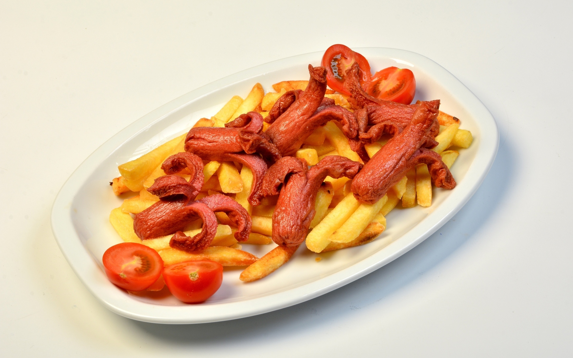 Картофель фри на тарелке с помидорами и сосисками