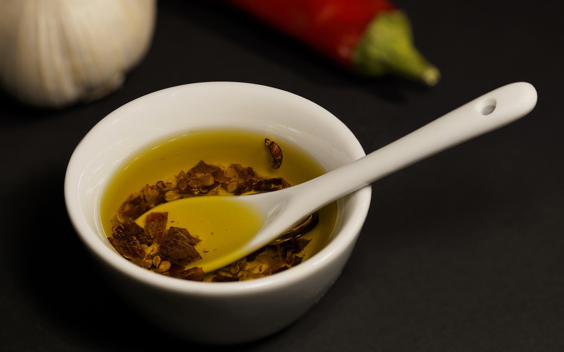 Оливковое масло в тарелке на столе с перцем и чесноком