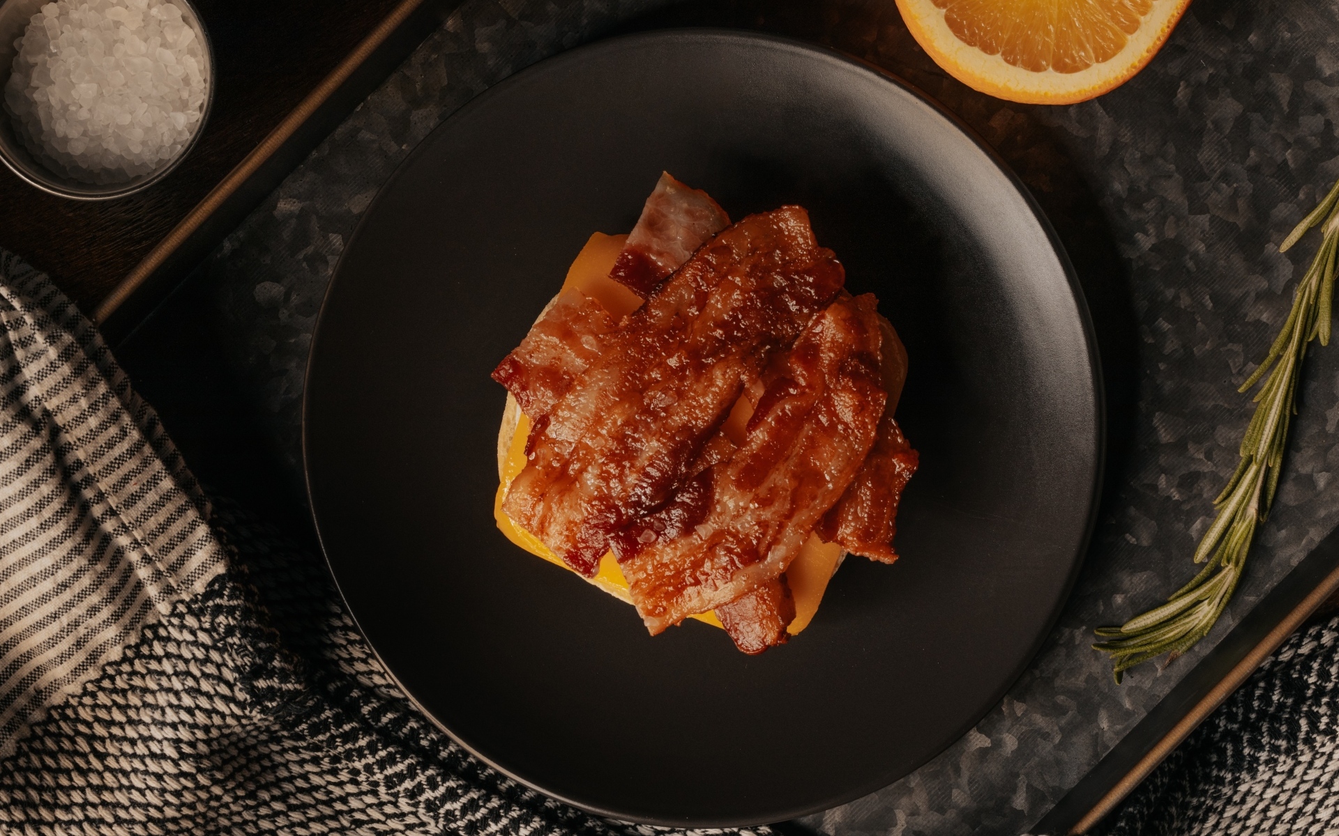 Бутерброд с сыром и жареным беконом на тарелке