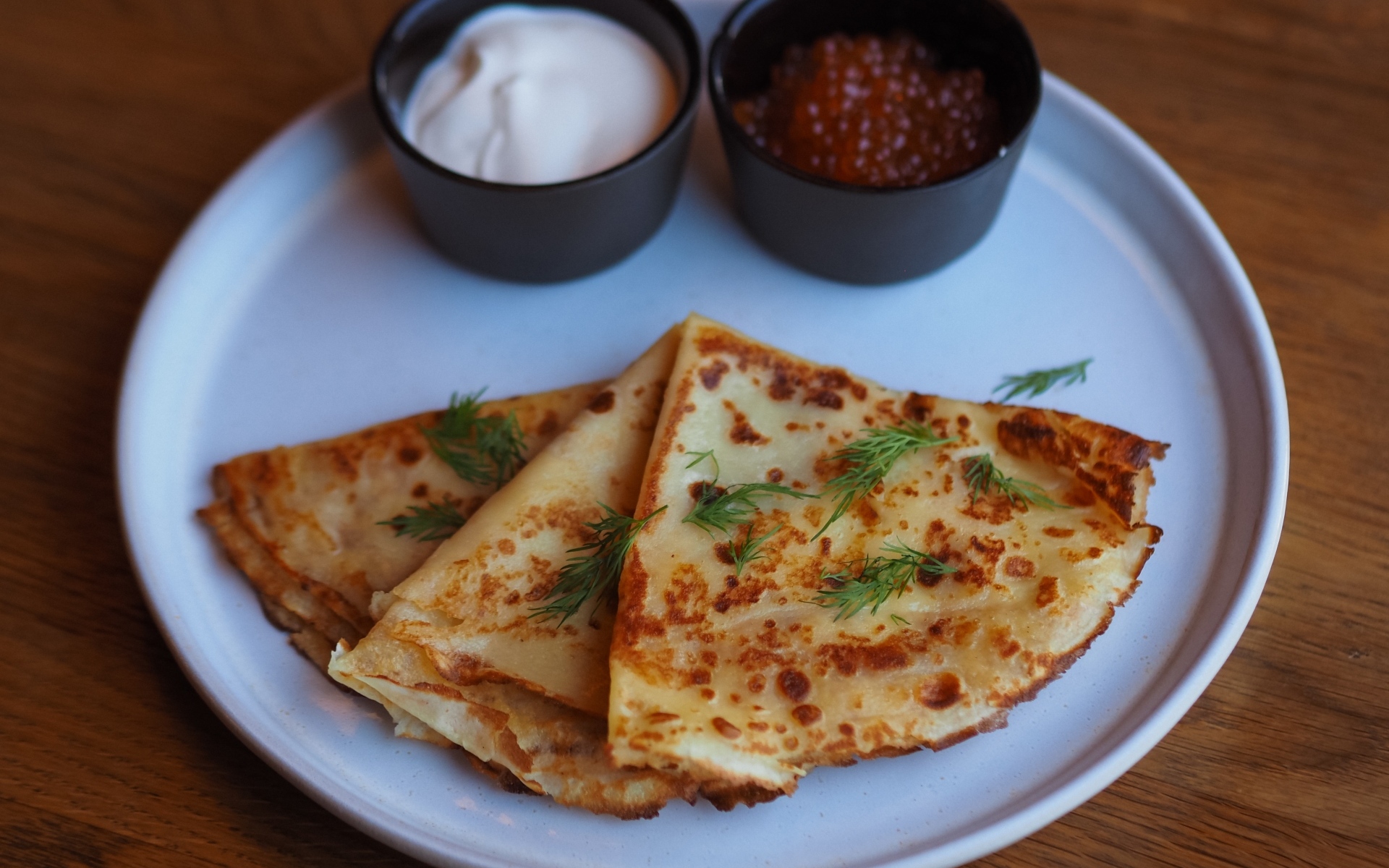 Тонкие блинчики на тарелке с красной икрой и сметаной