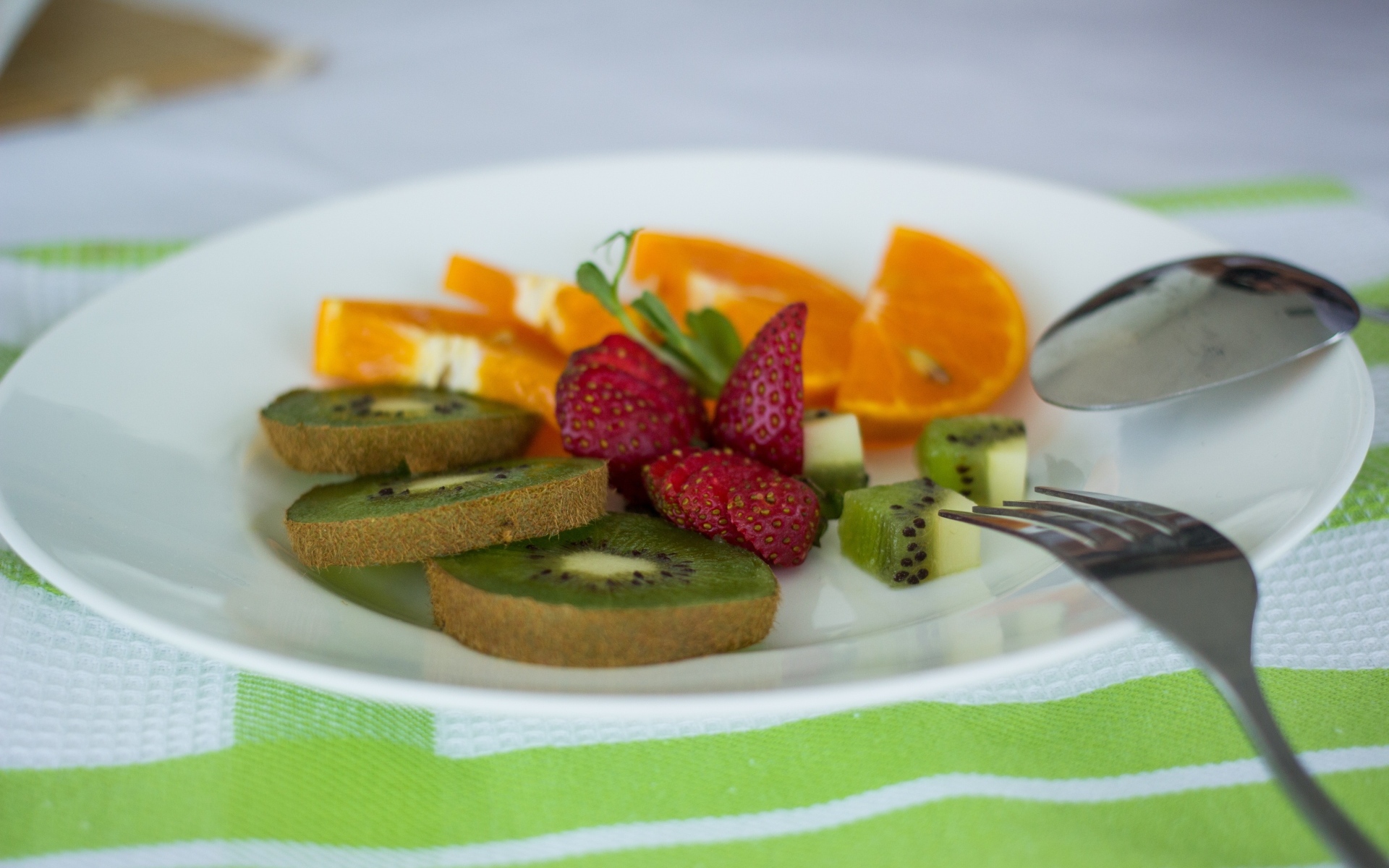 Свежие нарезанные фрукты на тарелке с вилкой