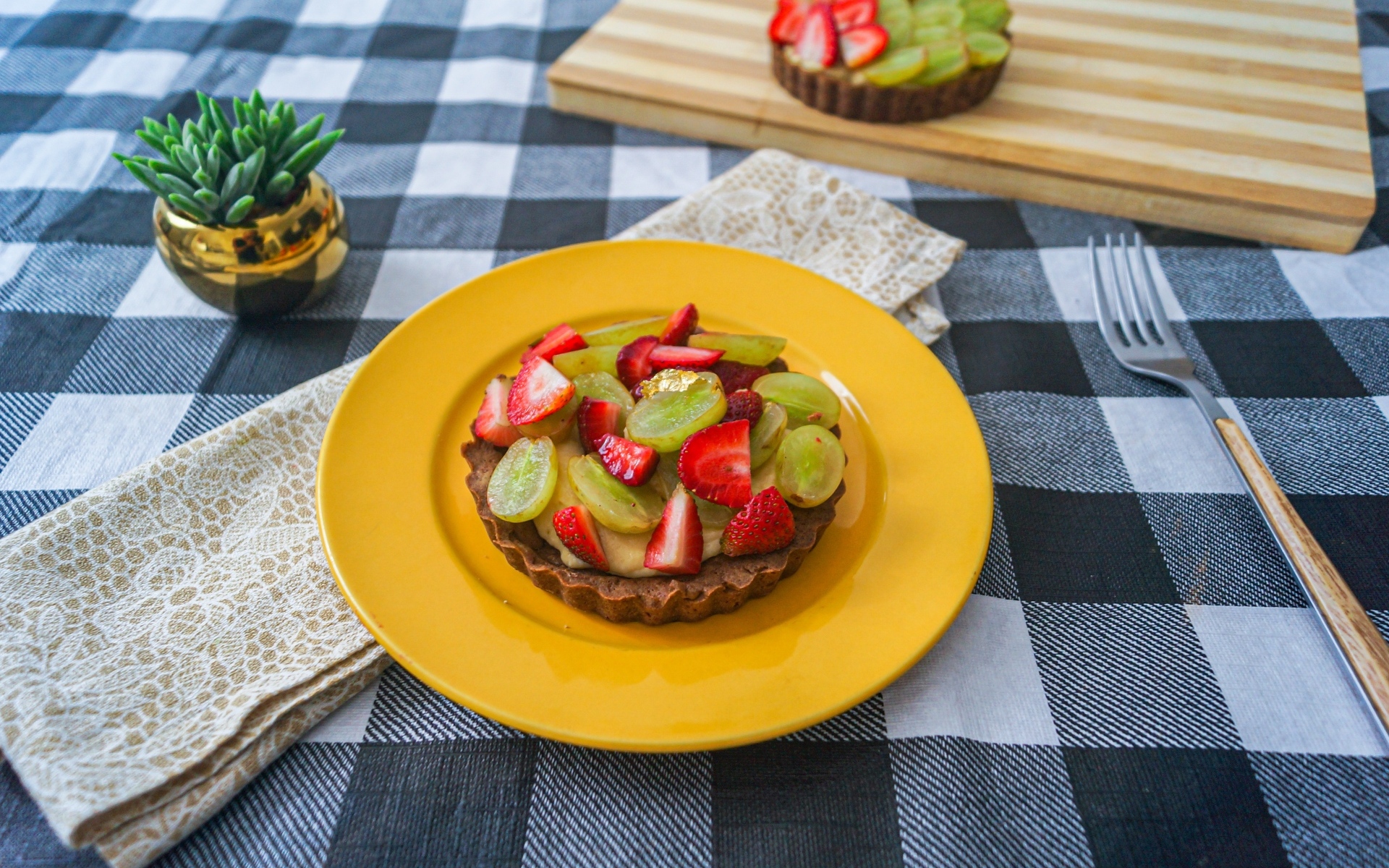 Пирожное с кремом и ягодами клубники и винограда