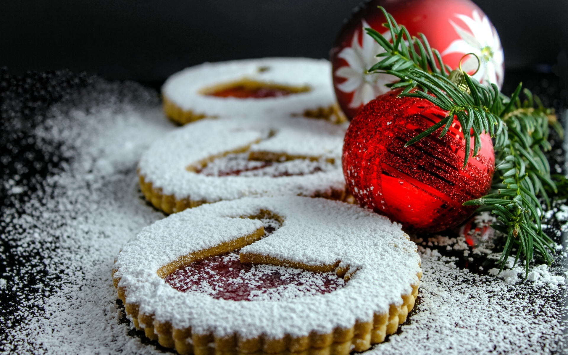 Вкусное сладкое печенье в сахарной пудре на столе с елочными игрушками