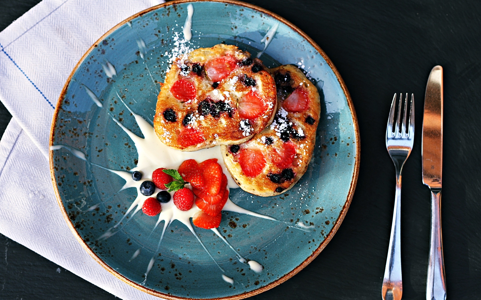 Оладьи на тарелке с ягодами и сметаной