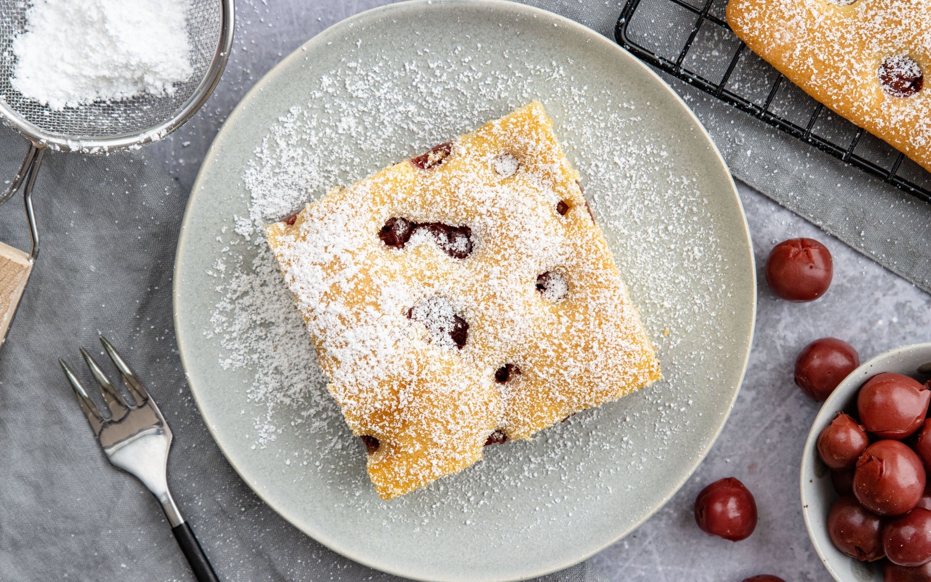 Кусок вишневого пирога на тарелке с сахарной пудрой