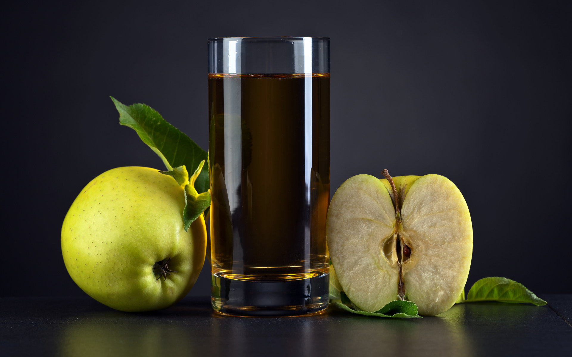 Стакан сока с зелеными яблоками на сером столе