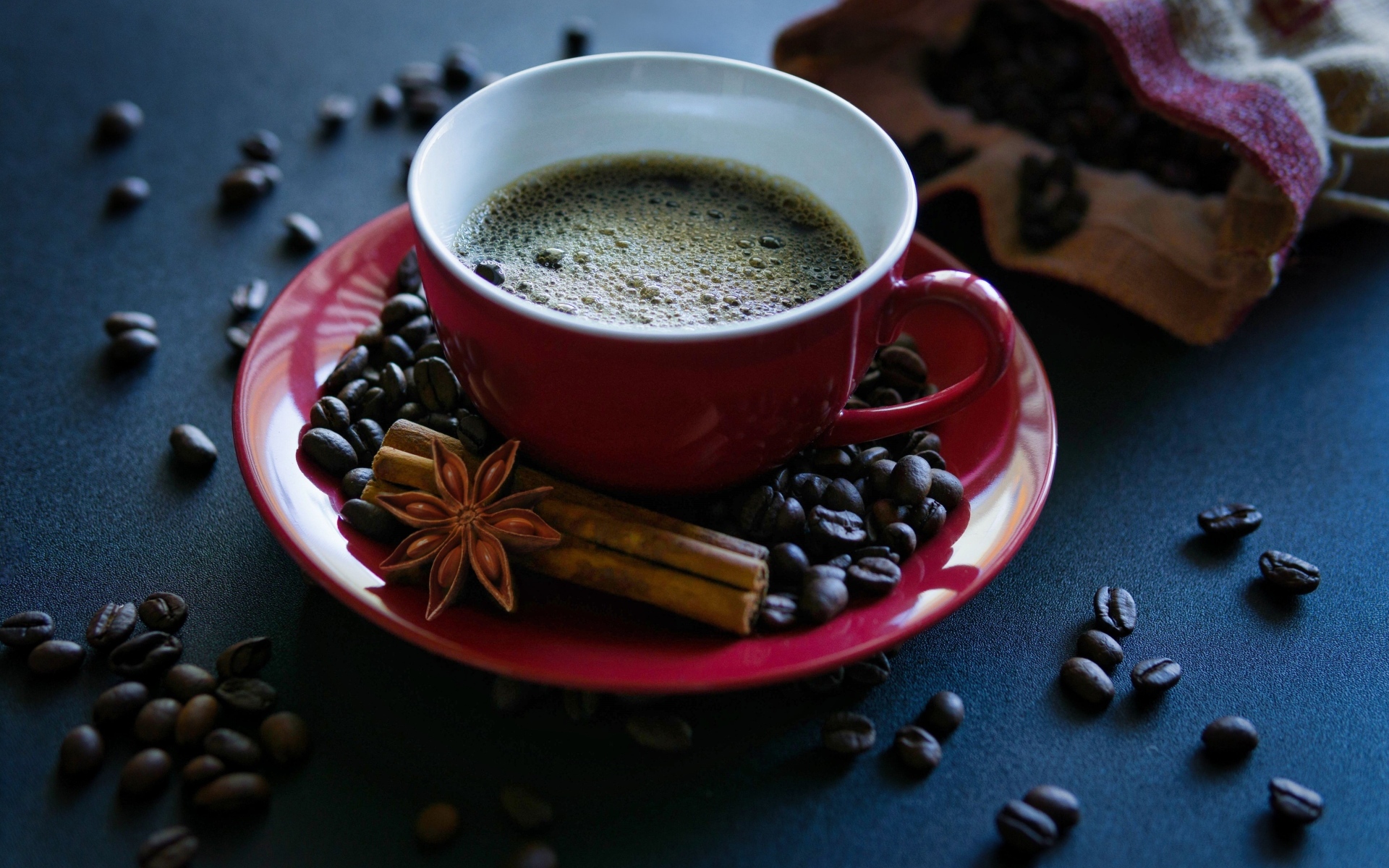 Красная чашка кофе на столе со специями и зернами