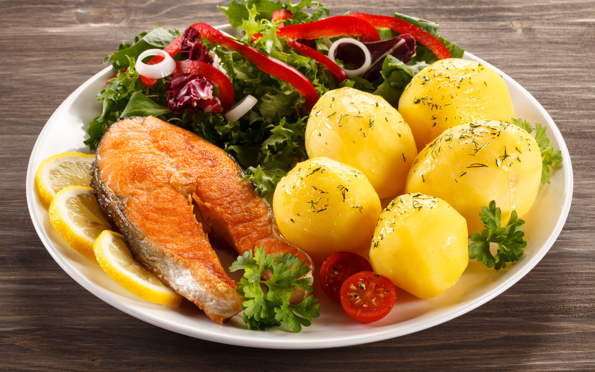 Картофель с кусочками рыбы и зеленью на тарелке