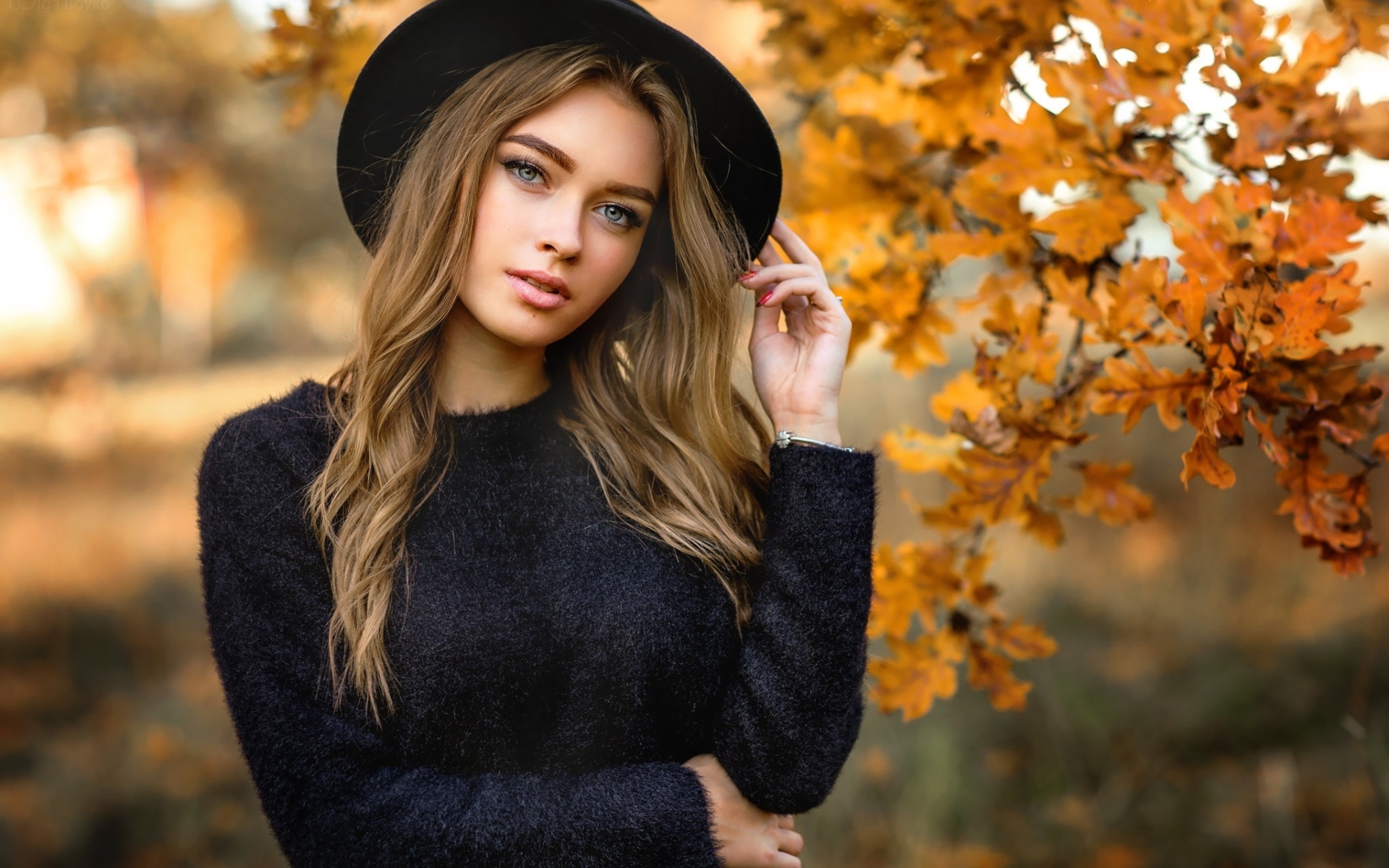 Девушка в черной шляпе стоит у дуба