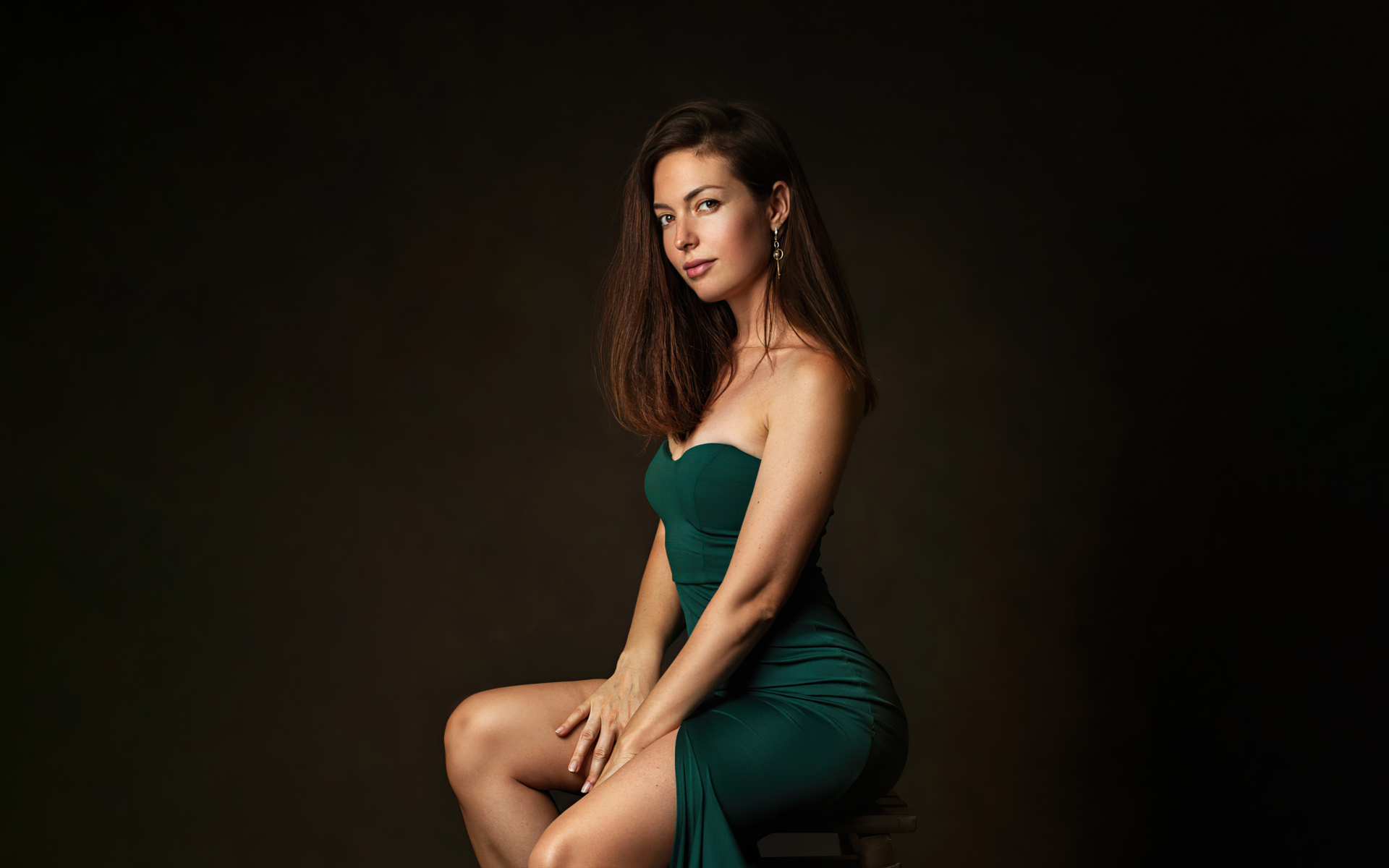 Девушка в зеленом платье сидит на стуле