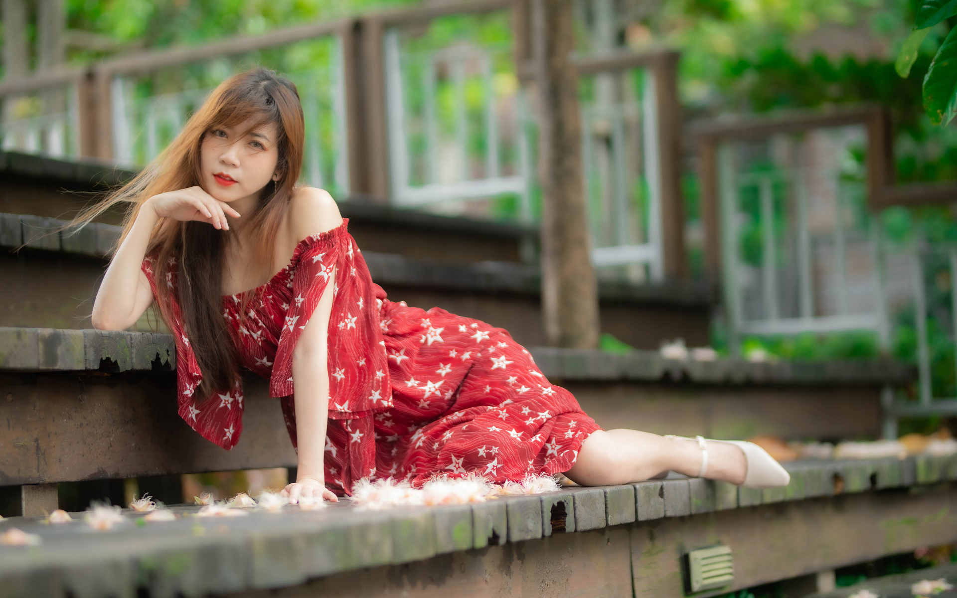 Девушка азиатка лежит на ступеньках в красном платье