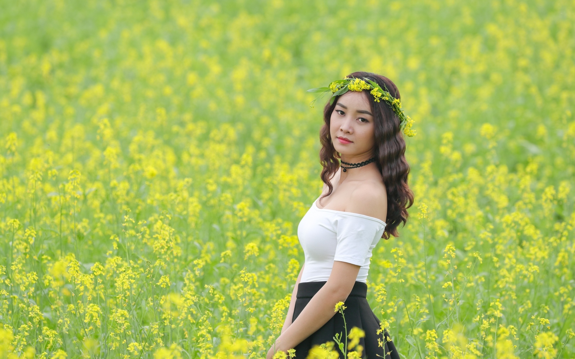 Девушка азиатка стоит на рапсовом поле