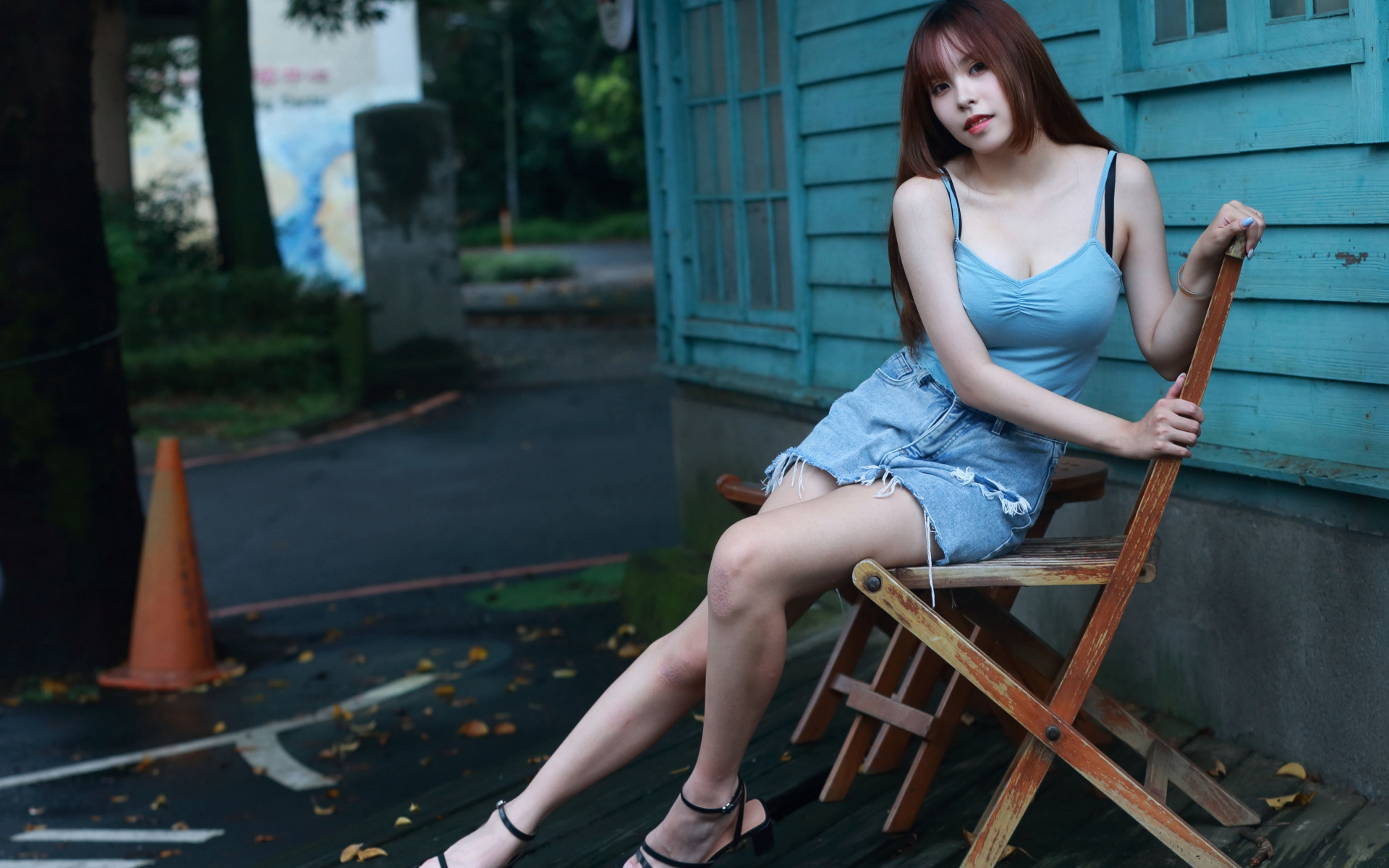 Красивая девушка сидит на стуле у дома