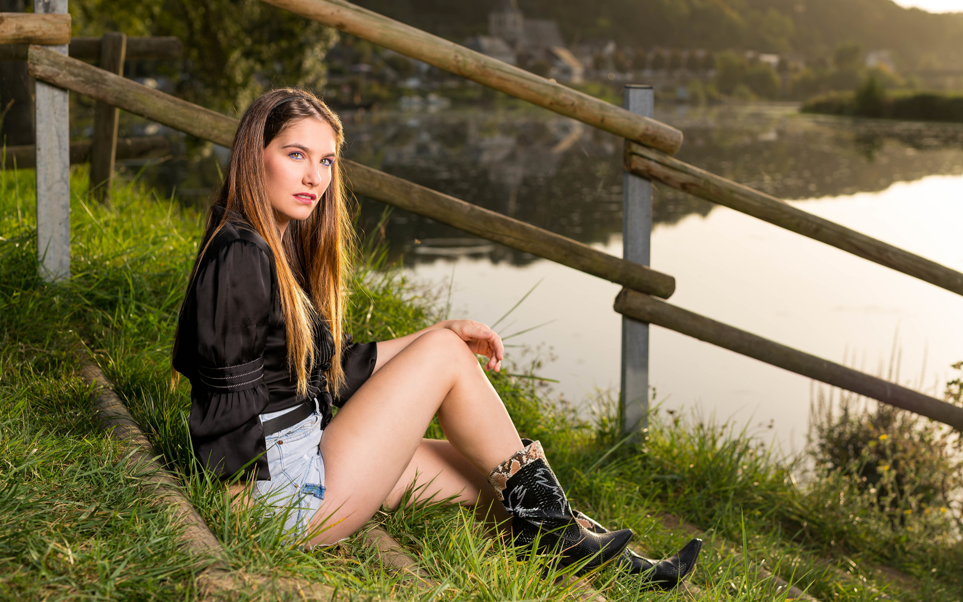 Красивая девушка сидит на берегу реки