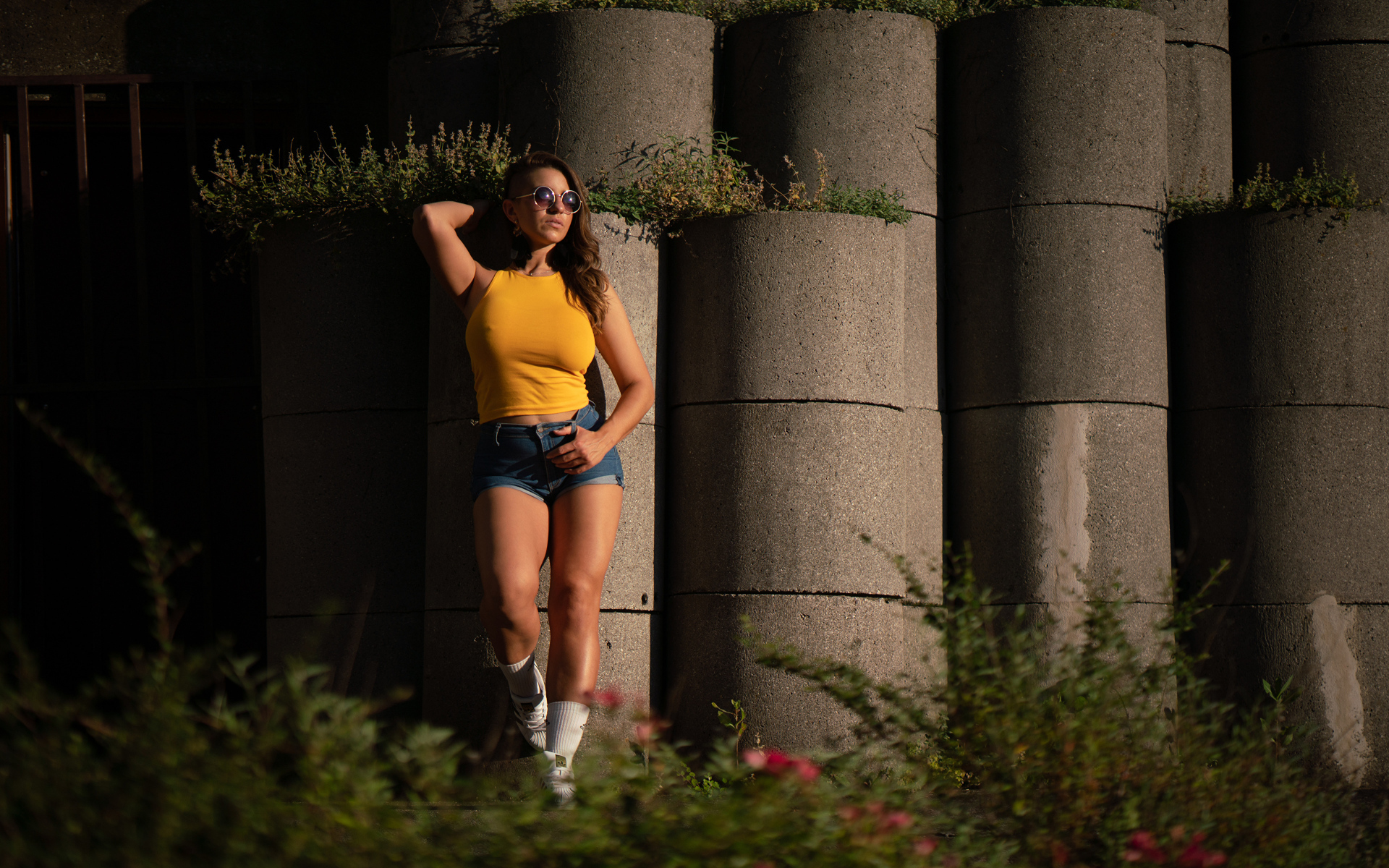 Красивая девушка в очках стоит у стены