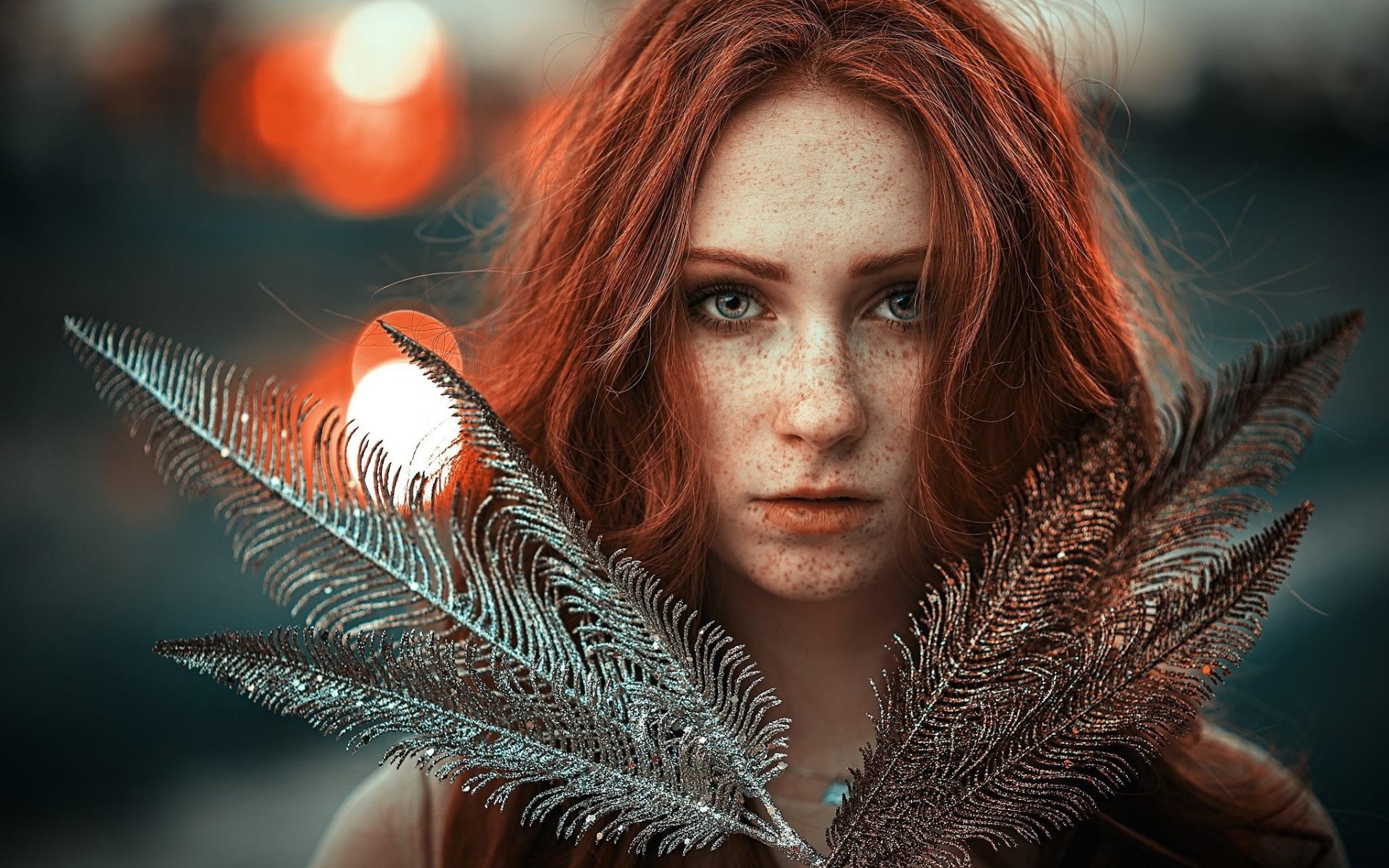 Яркая рыжеволосая девушка с перьями в руках