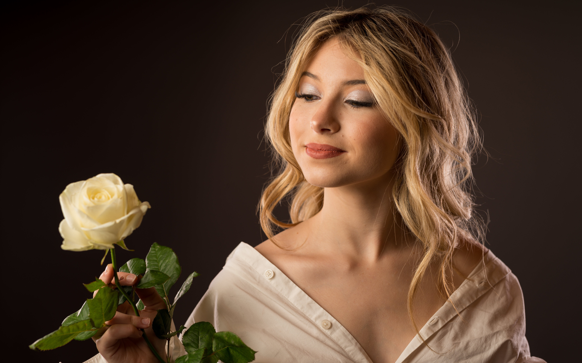 Милая девушка в рубашке с розой в руках