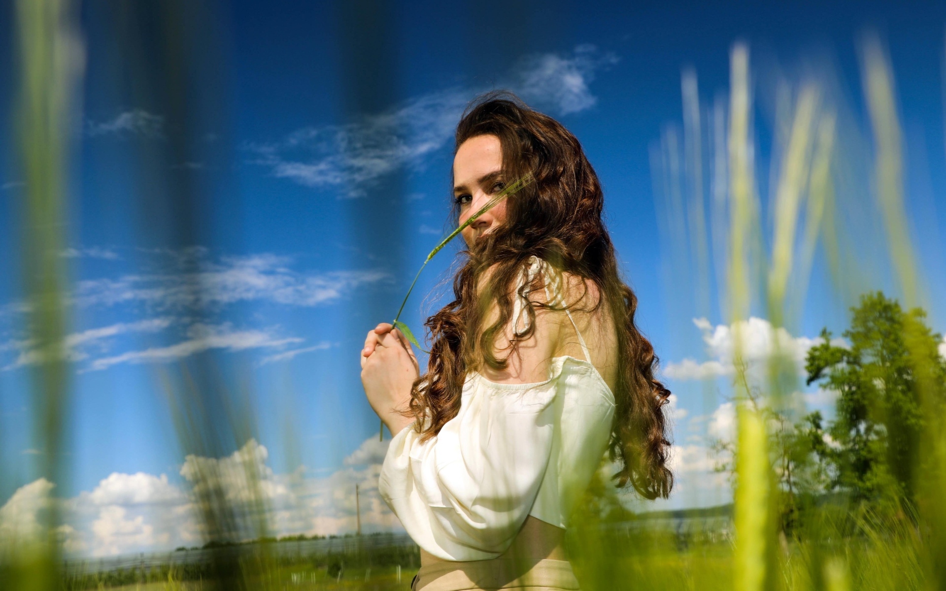 Милая девушка на поле на фоне голубого неба