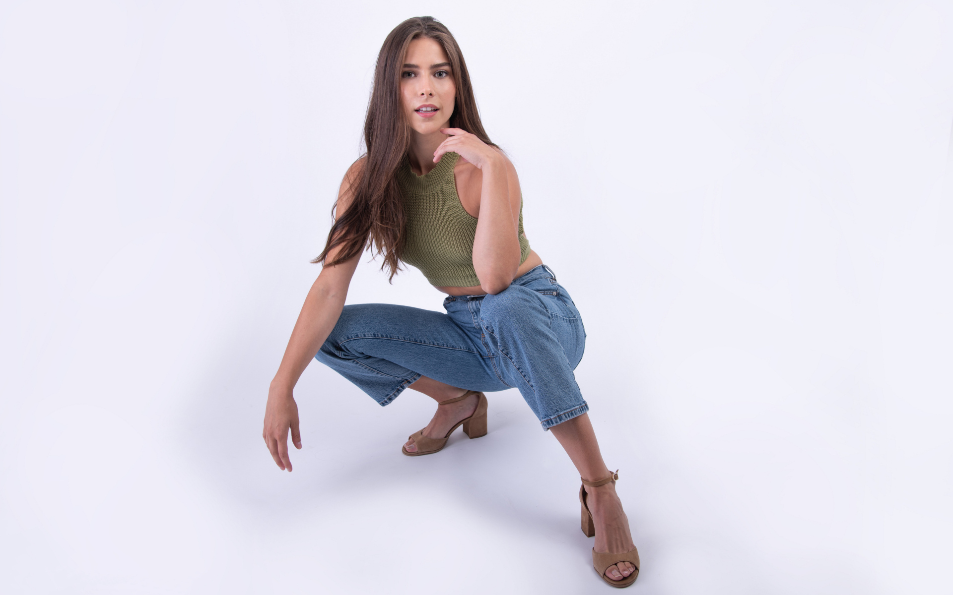 Девушка сидит на корточках на белом фоне