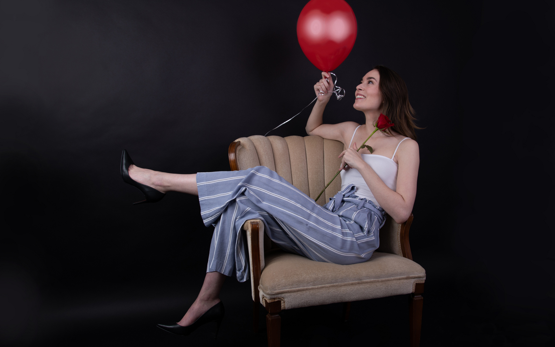 Девушка с шариком и розой сидит в кресле