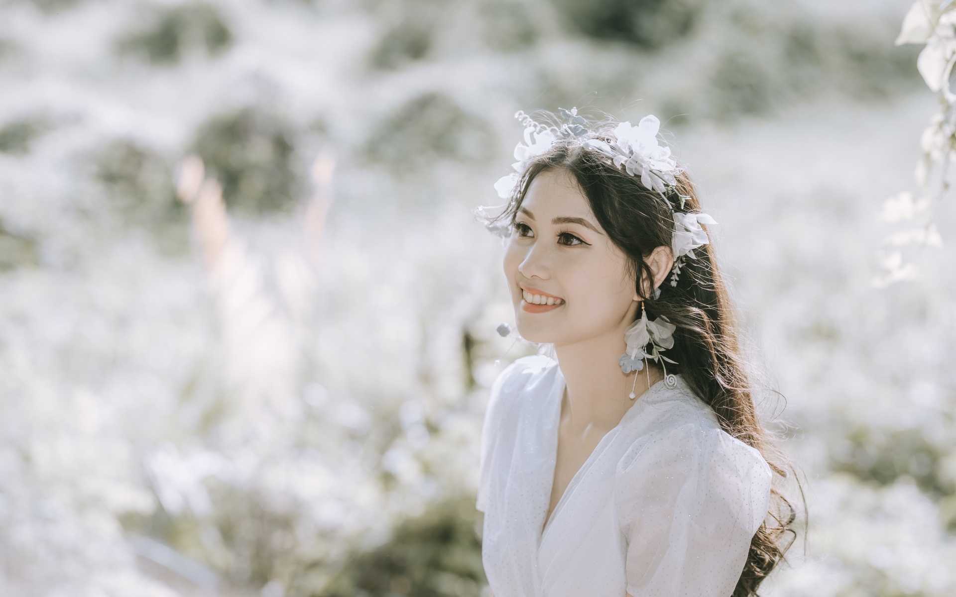 Улыбающаяся девушка азиатка в белом платье на поле