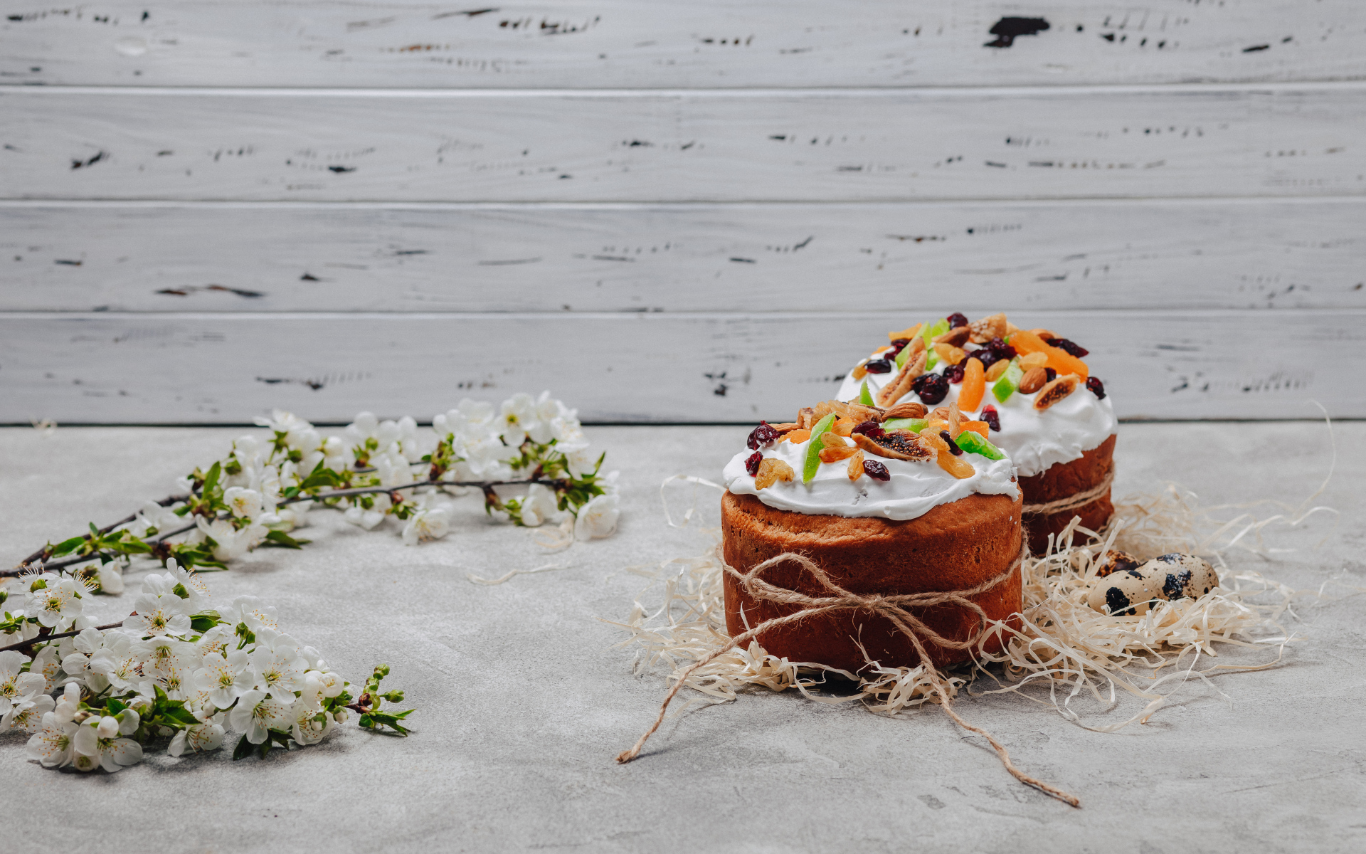 Красивые пасхальные куличи с веткой вишни на сером столе на Пасху