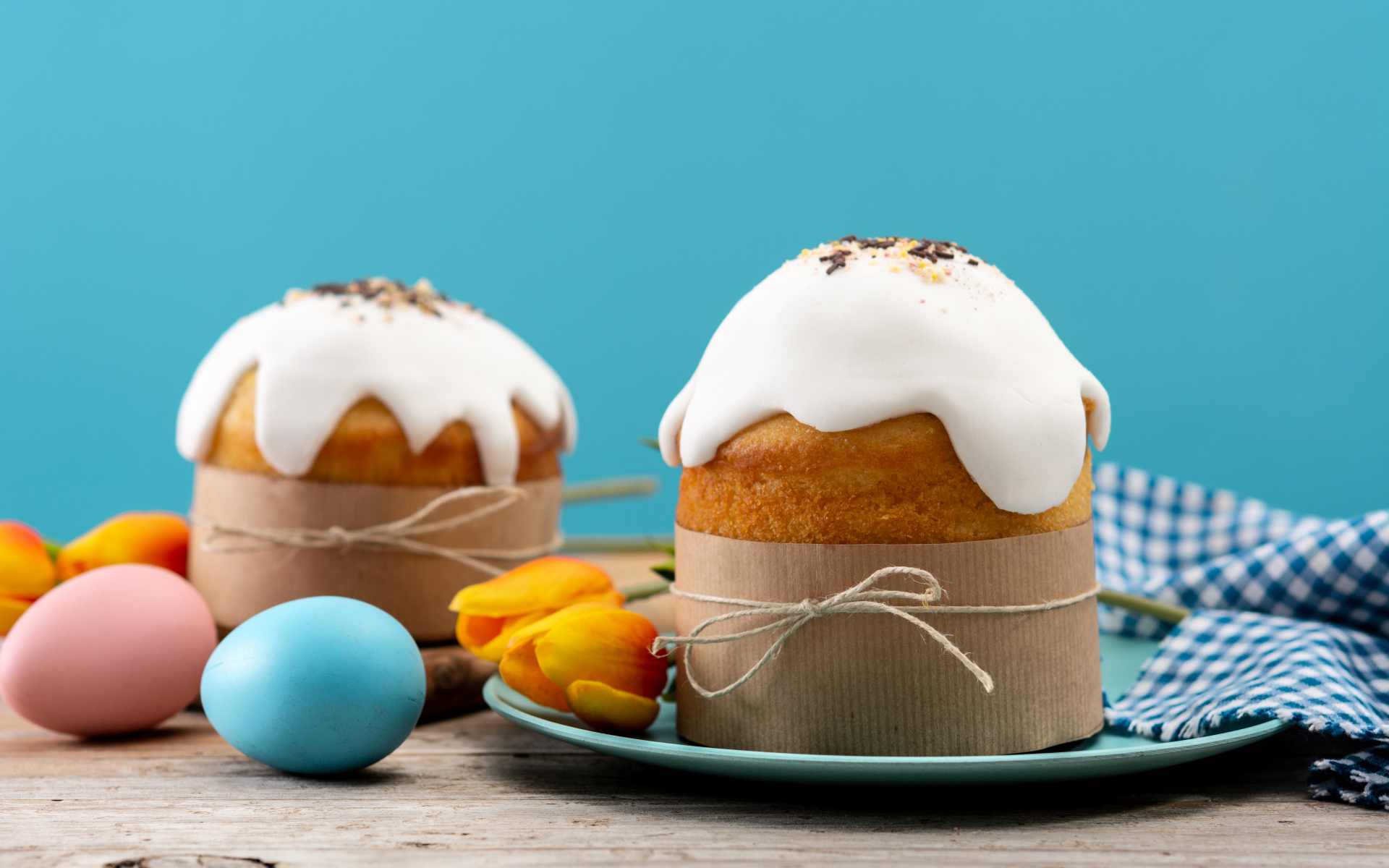 Пасхальные куличи с белой глазурью на столе с яйцами