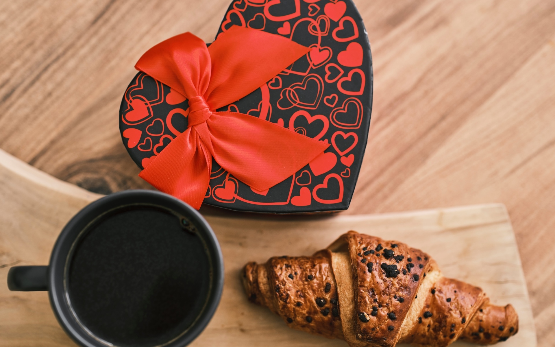 Коробка в форме сердца, кофе и круассан на столе