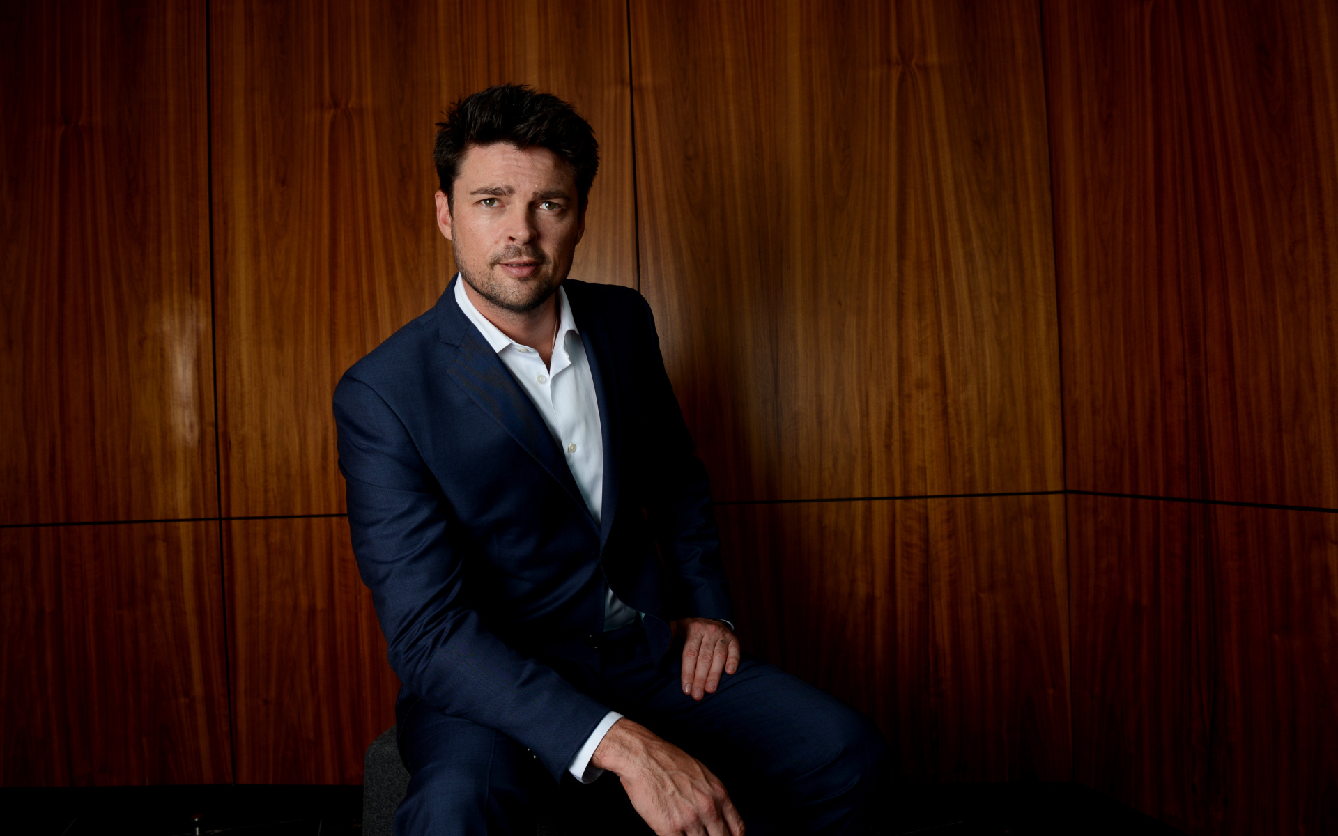 Актер Карл Урбан в костюме на фоне стены