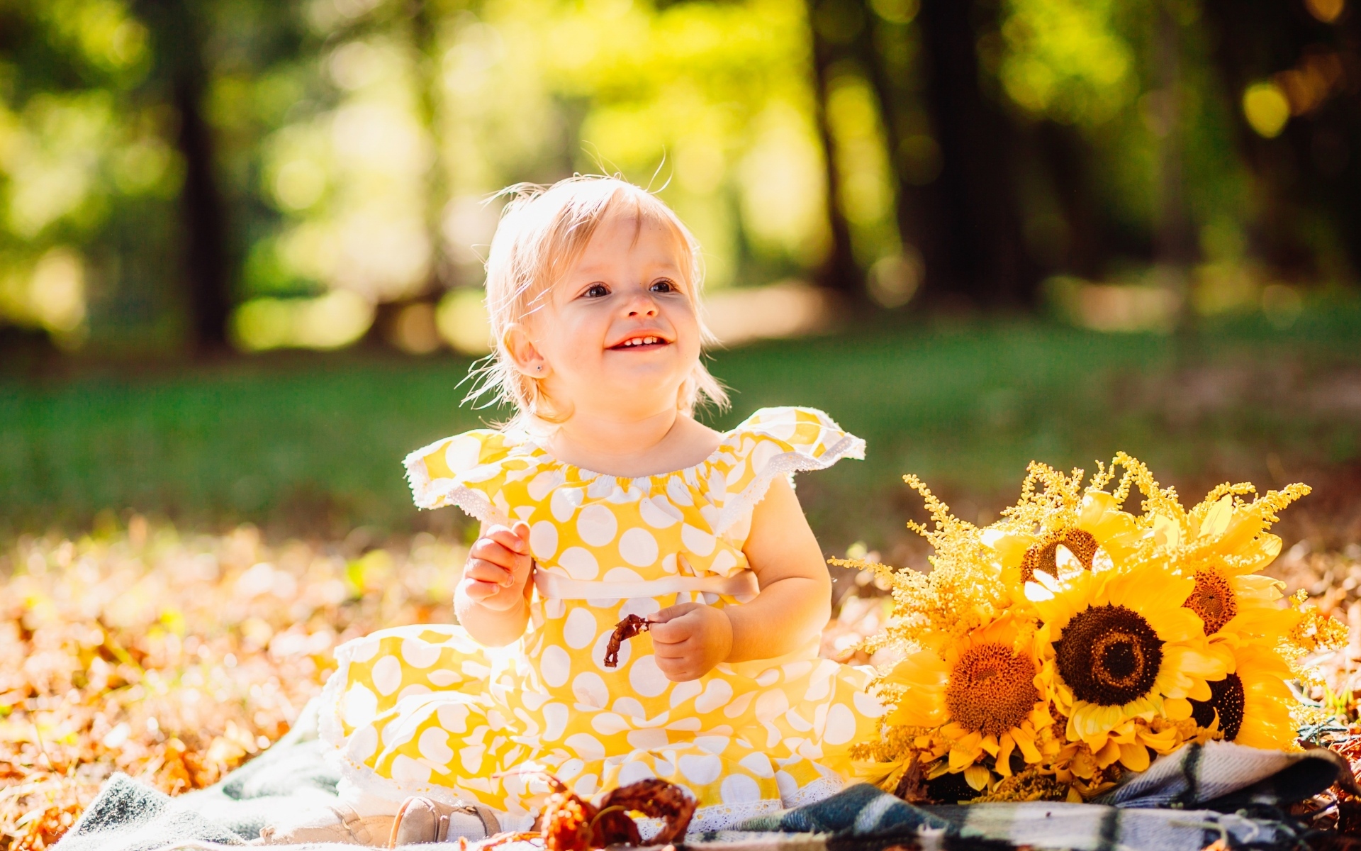 Малышка с цветами подсолнуха на траве