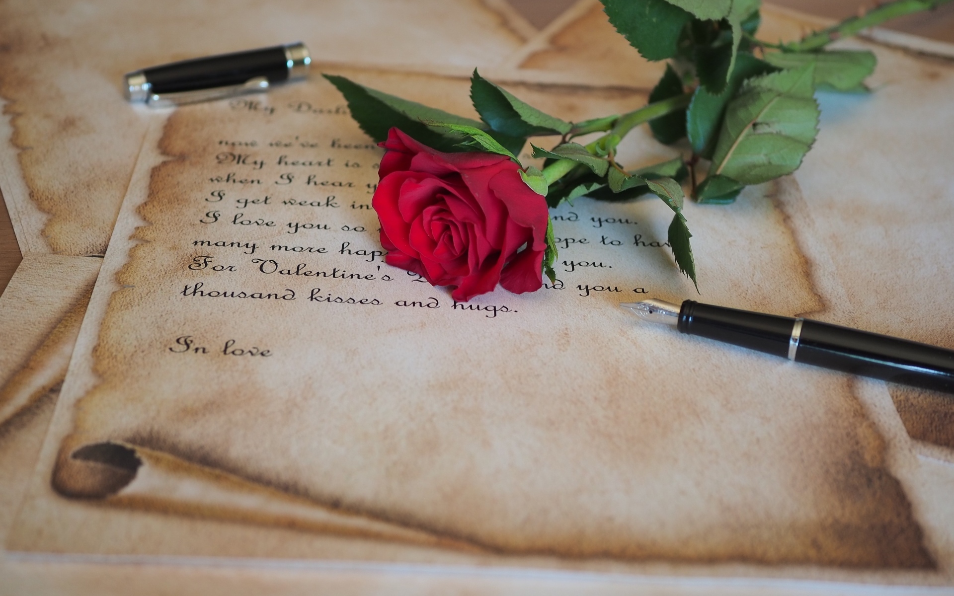 Красная роза с запиской и ручкой на столе