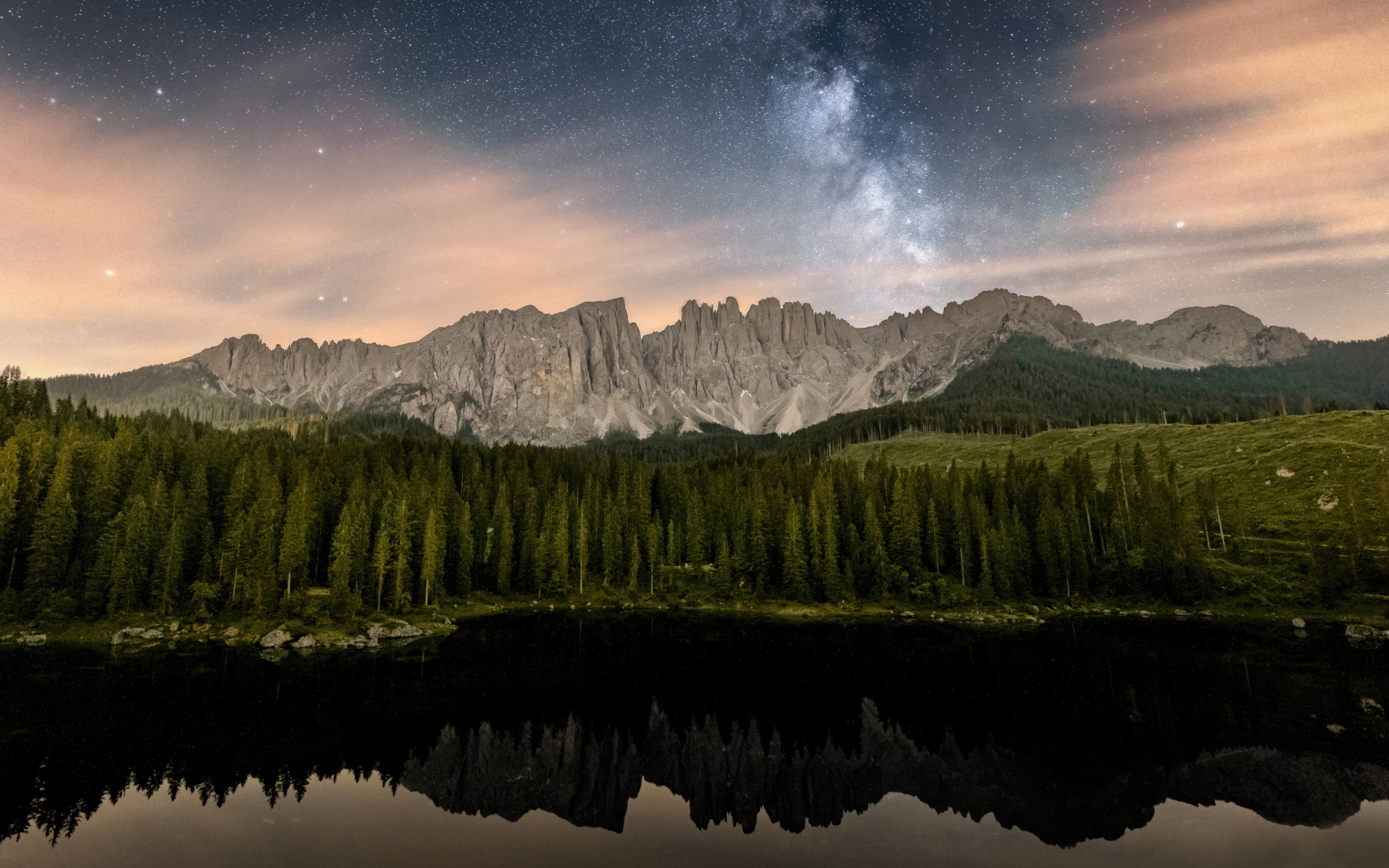 Млечный путь над горами и лесом отражающимися в воде