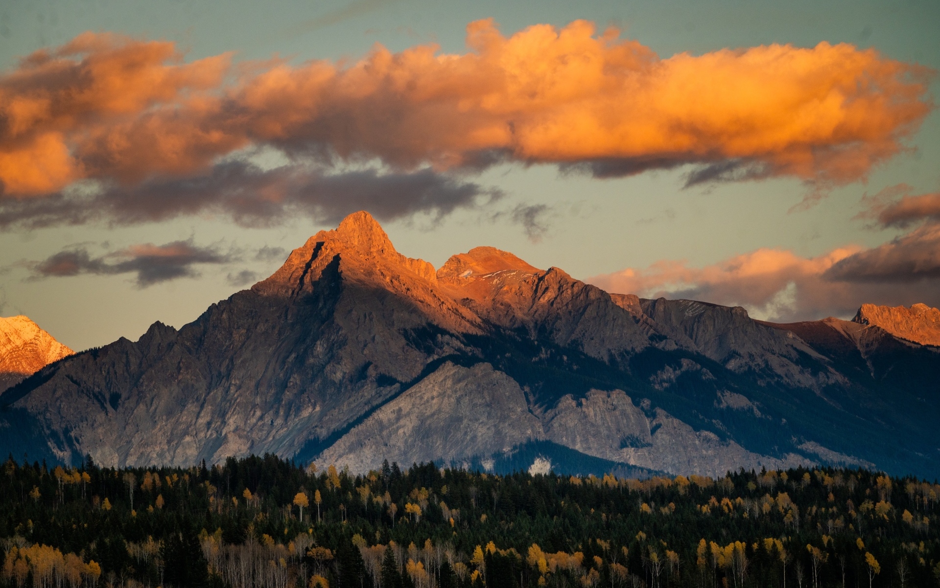 Солнце в облаках освещает вершину горы