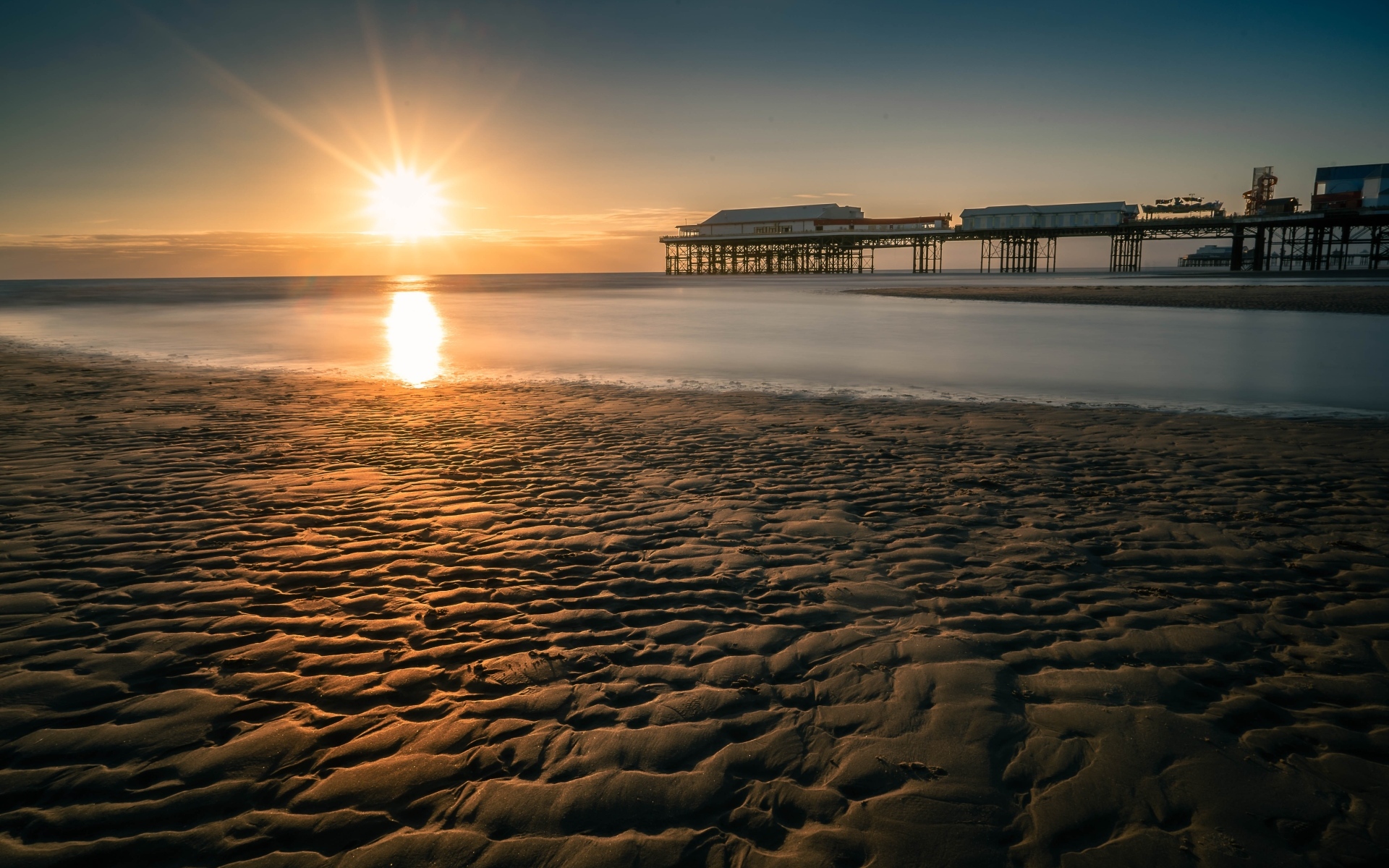 Мокрый песок на берегу моря на закате