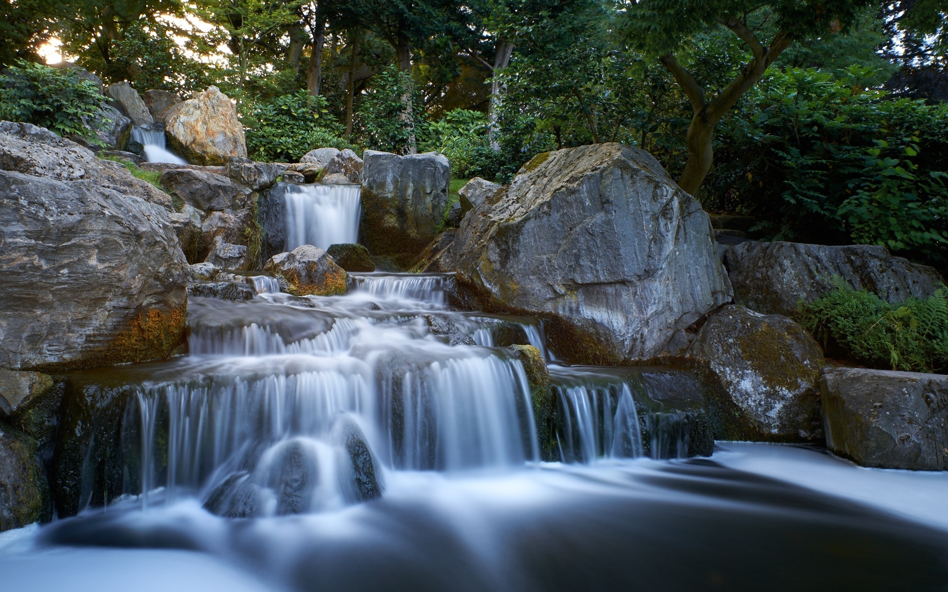 Водопад стекает по большим холодным камням в лесу