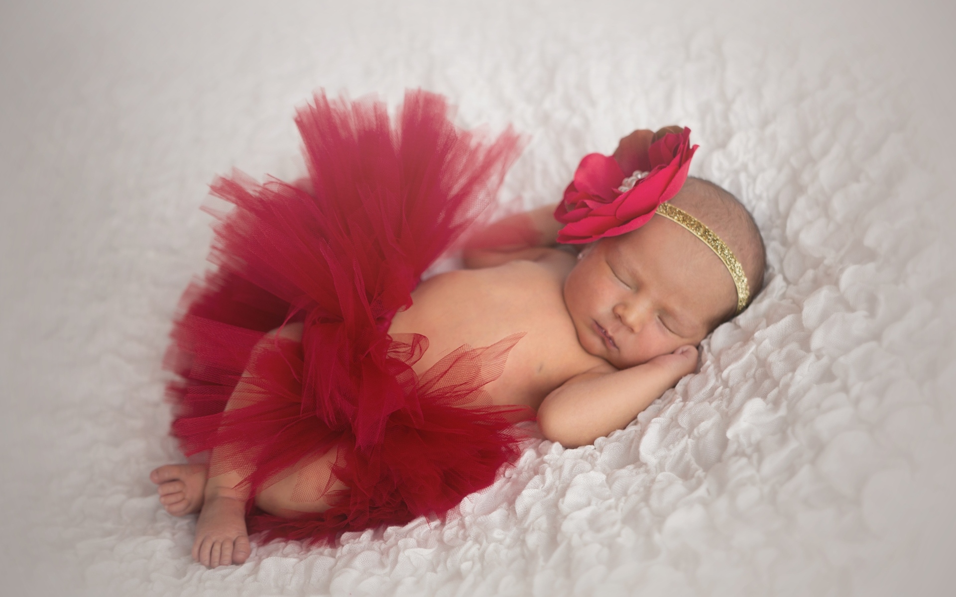 Красивая пышная красная юбка и бант на спящей малышке