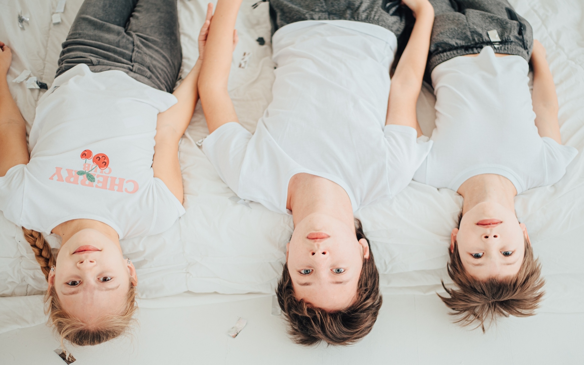 Дети в белых футболках лежат на кровати