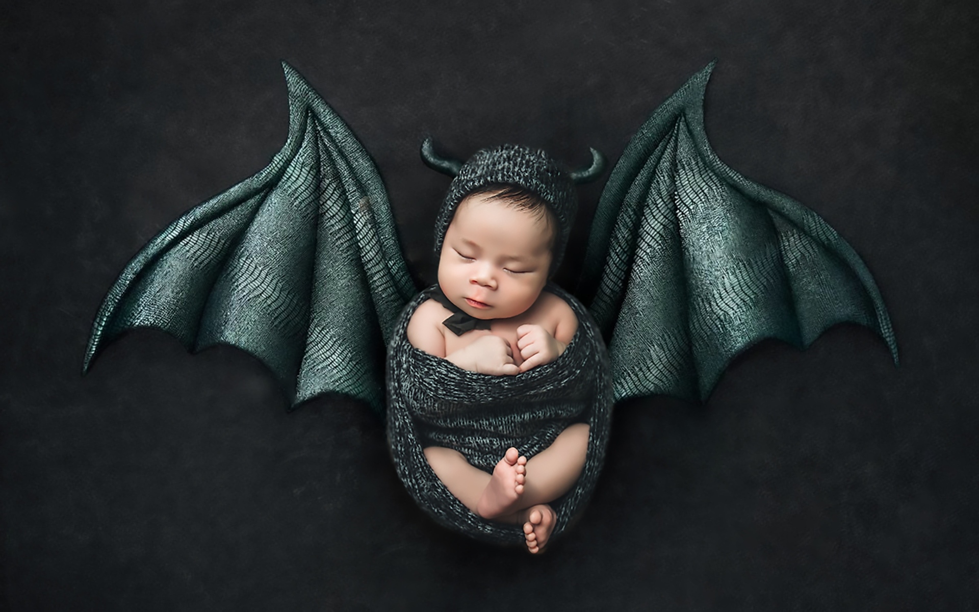 Маленький спящий ребенок с крыльями на Хэллоуин