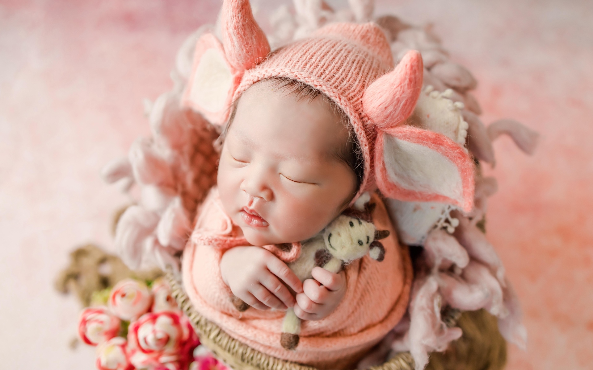 Маленький спящий новорожденный ребенок в шапке с рогами