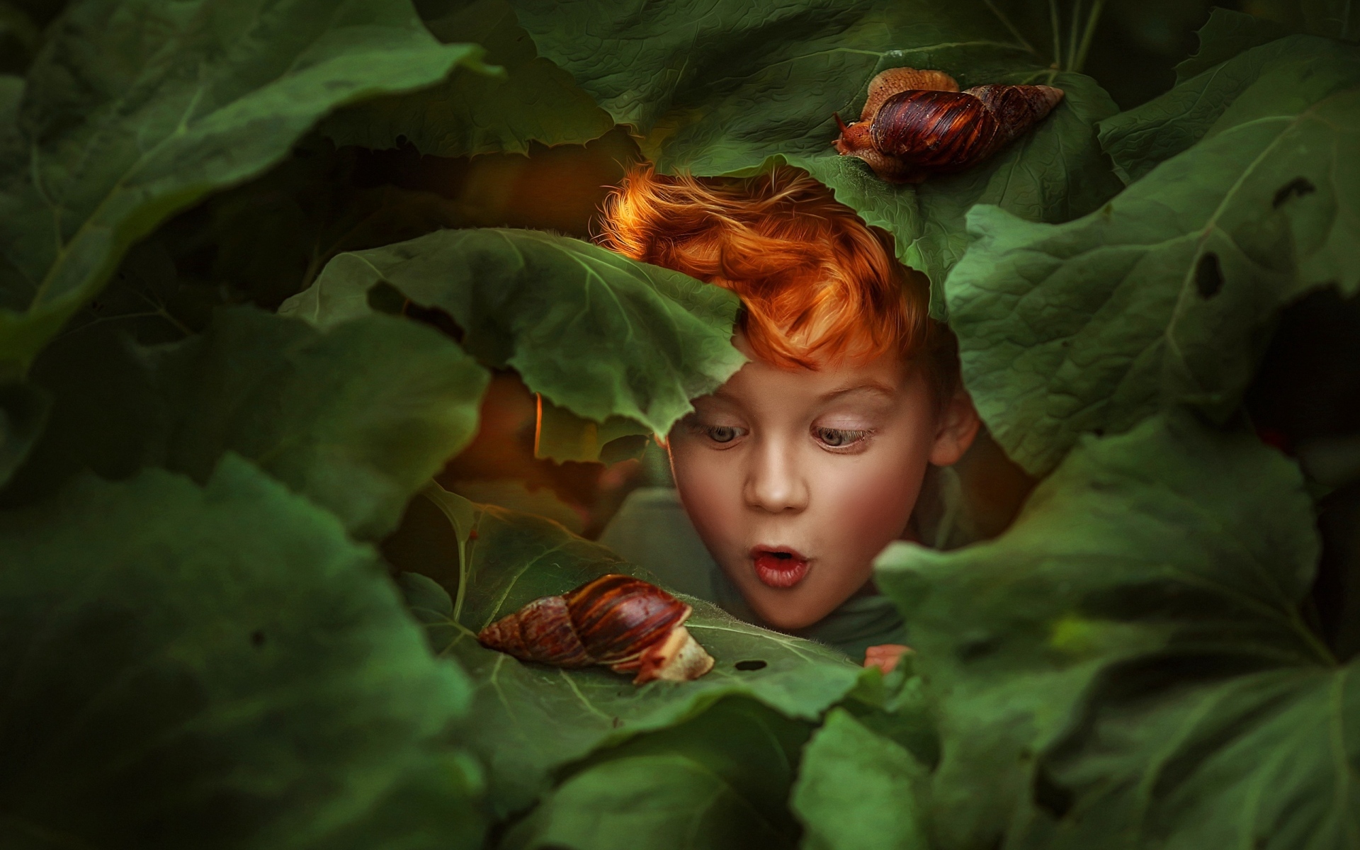 Удивленный рыжеволосый мальчик смотрит на улитку