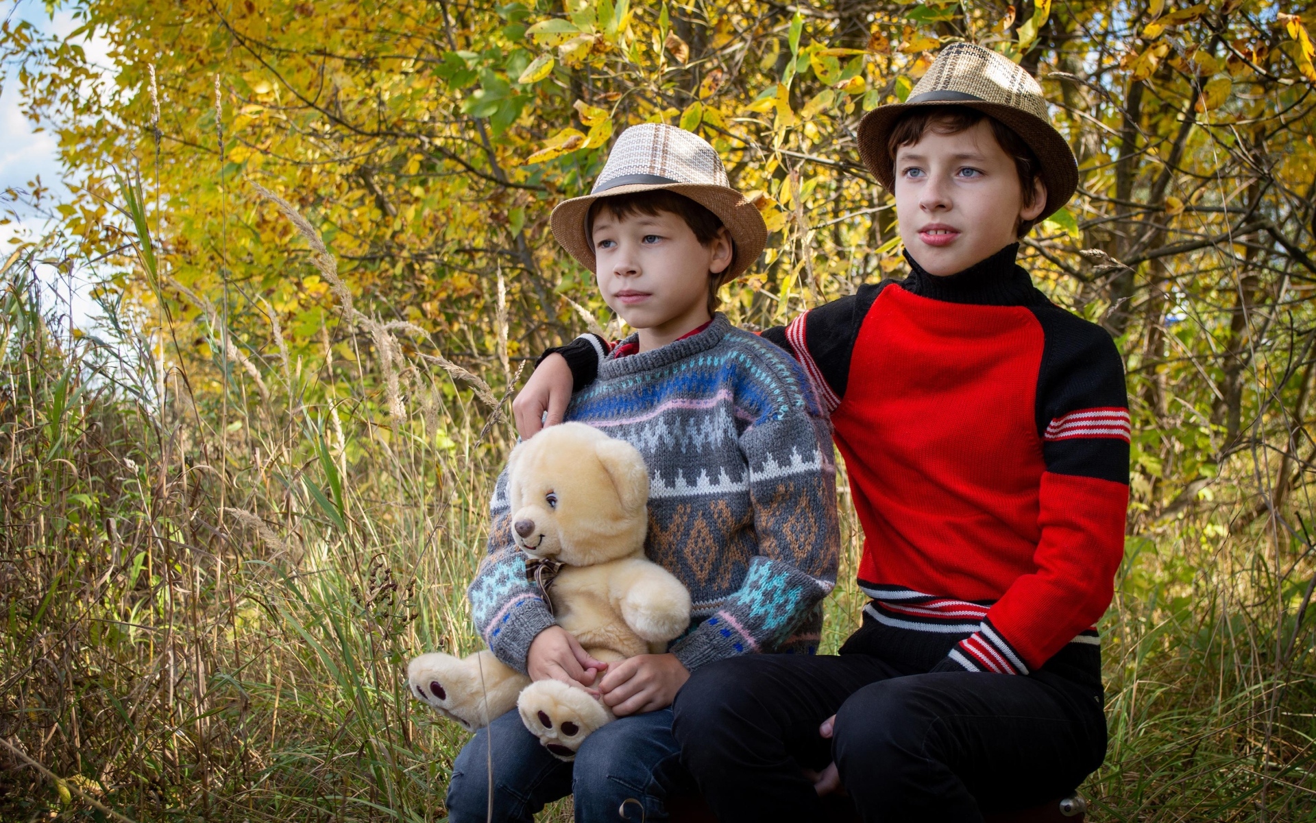 Два мальчика с игрушкой сидят у дерева