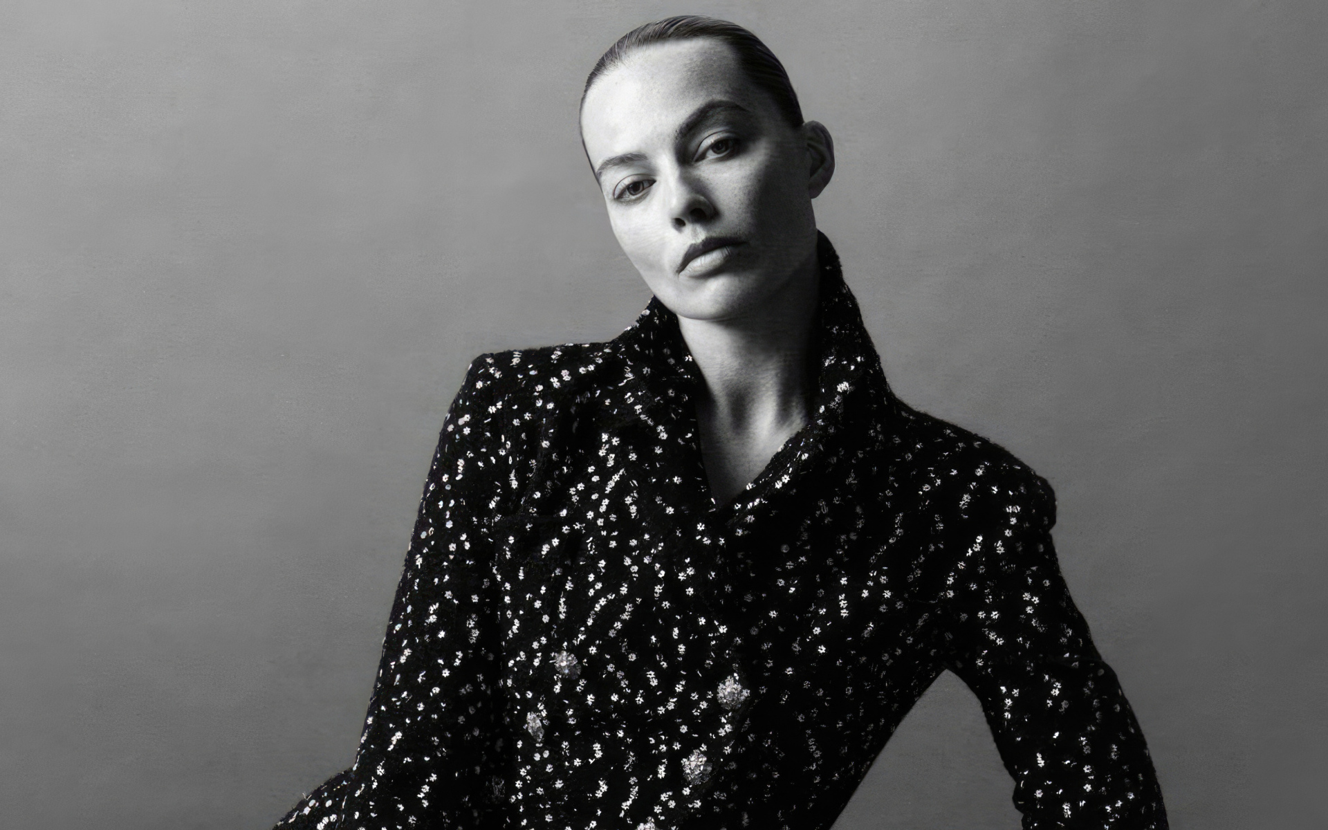 Грустная Марго Робби в блестящем пиджаке на сером фоне