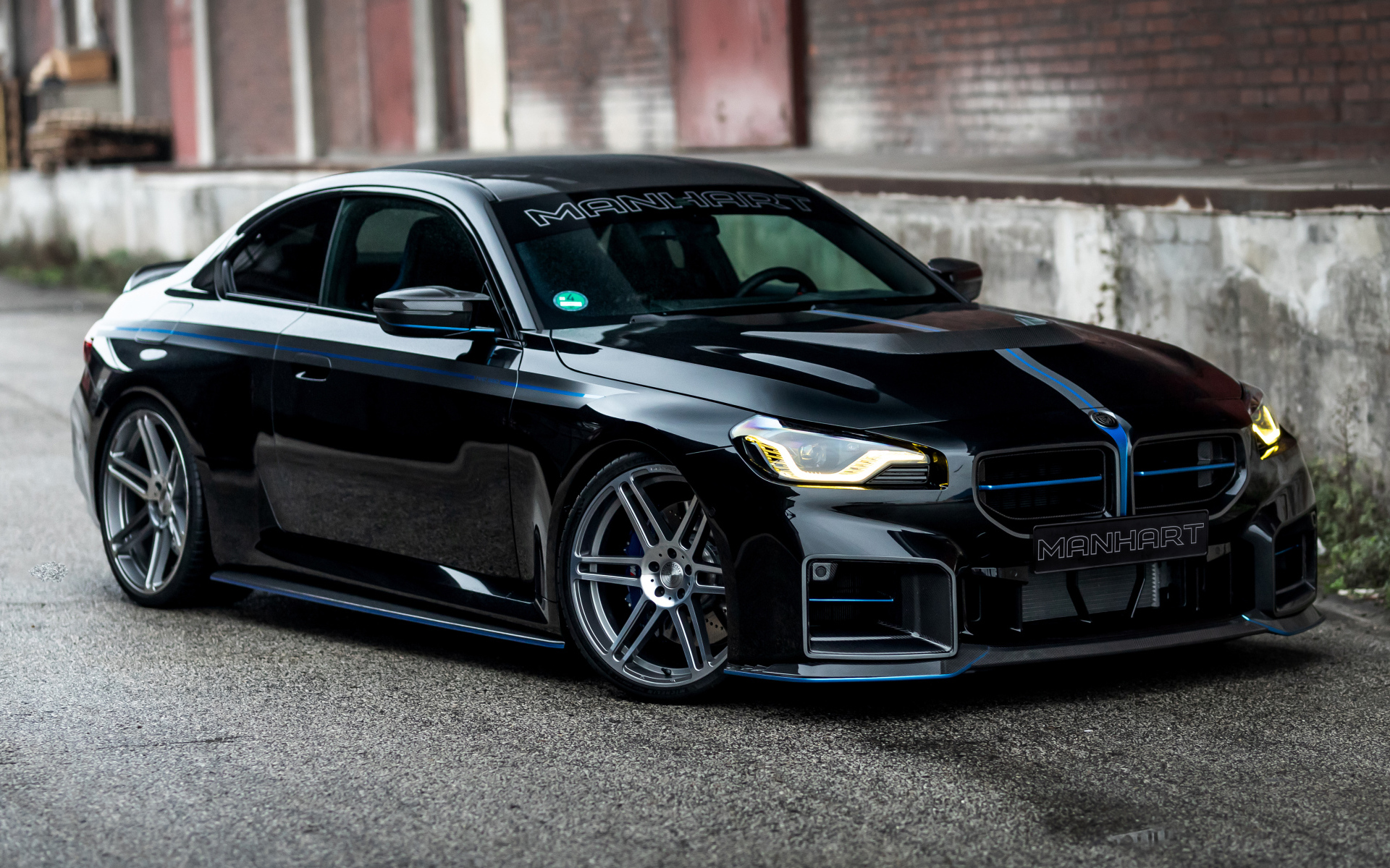 Черный автомобиль BMW M2 Manhart MH2 560 на сером фоне в городе