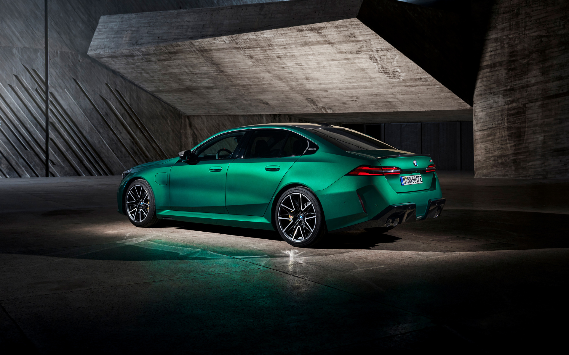 Вид сзади на зеленый автомобиль BMW M5 2024  года
