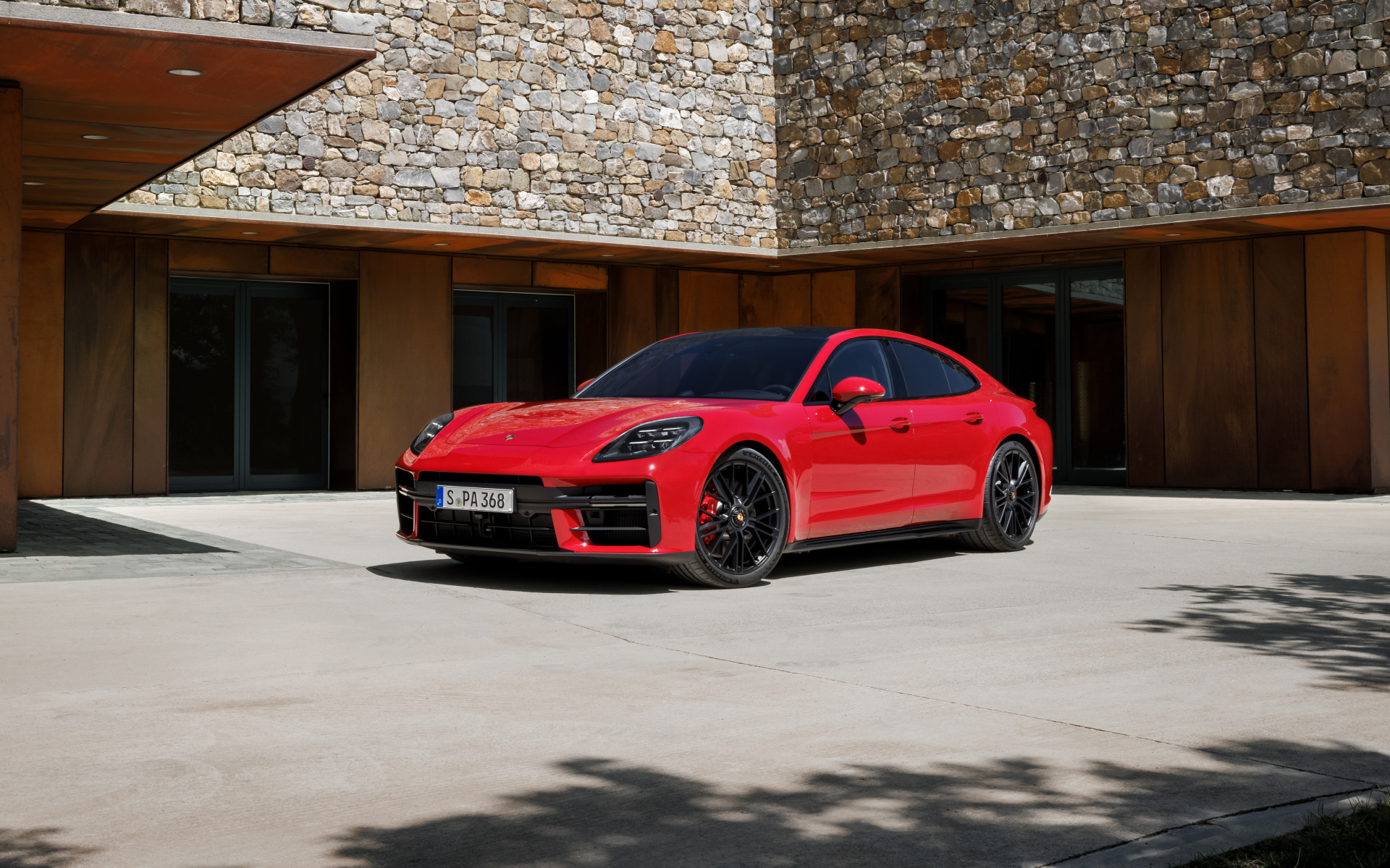 Красный автомобиль Porsche Panamera GTS 2024 года у здания