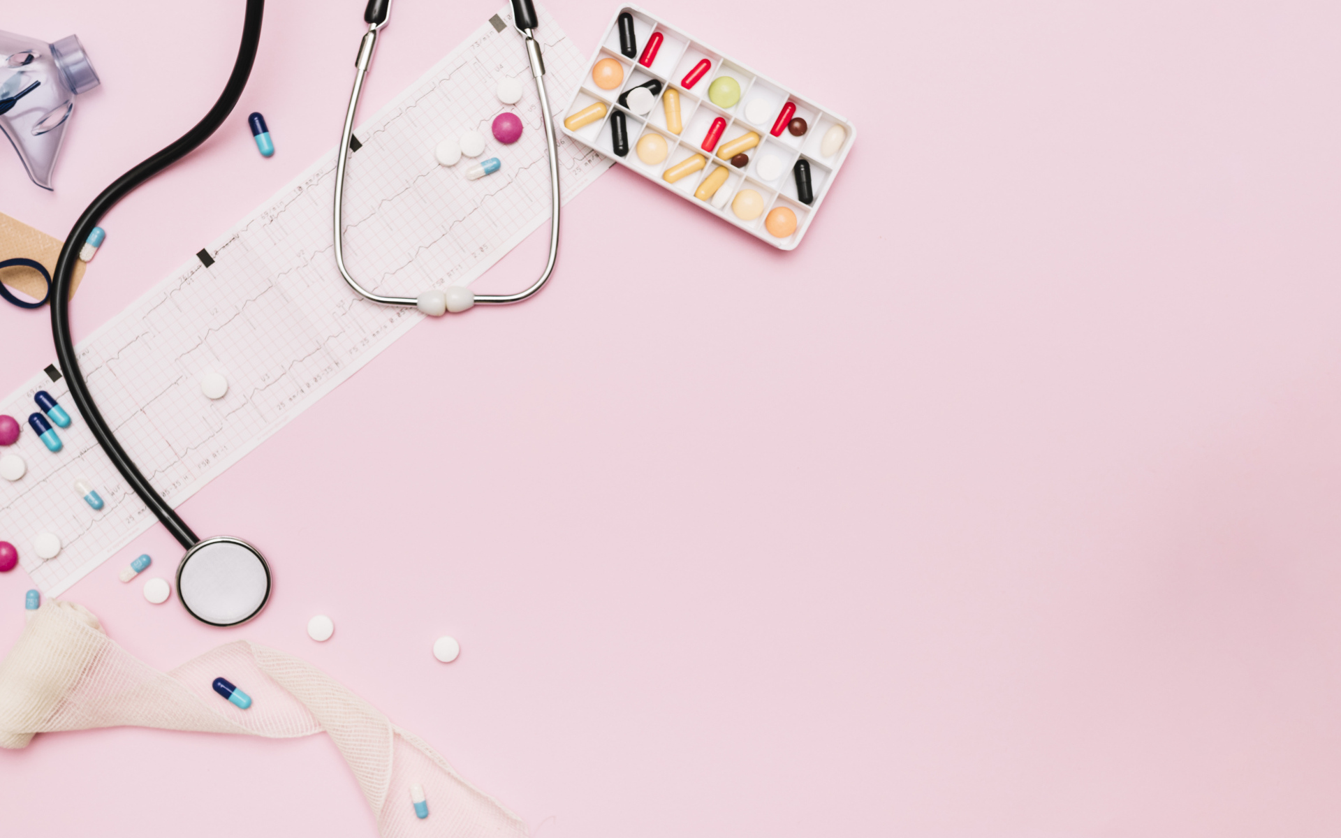 Стетоскоп и лекарства на кардиограмме на розовом фоне