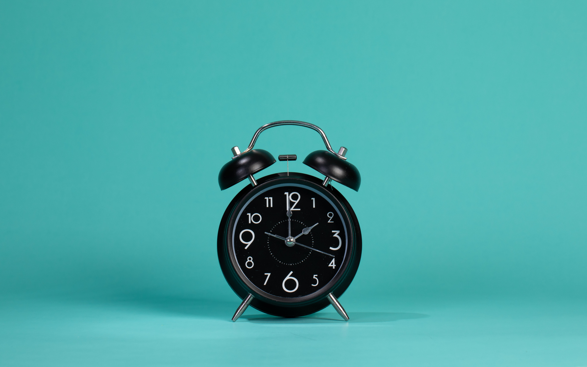 Черный будильник на голубом фоне