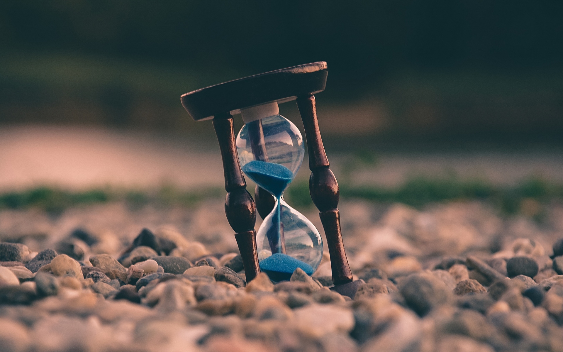Песочные часы лежат на мелких камнях