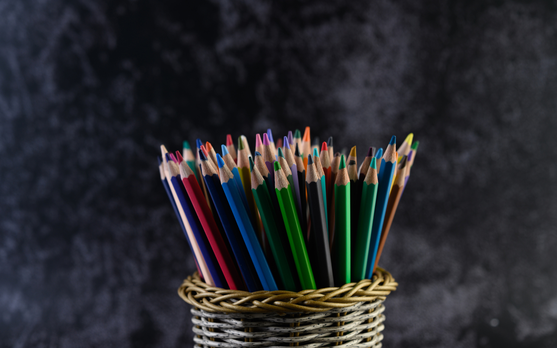 Разноцветные карандаши в стакане на сером фоне