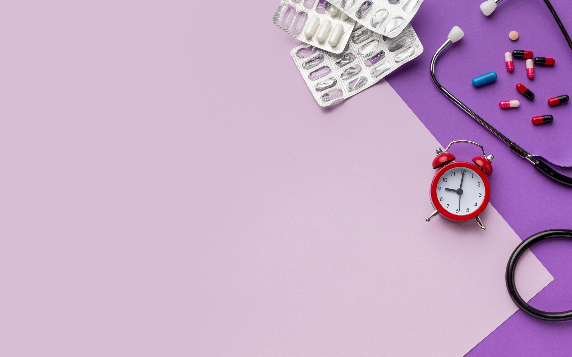 Таблетки, стетоскоп и будильник на сиреневом фоне